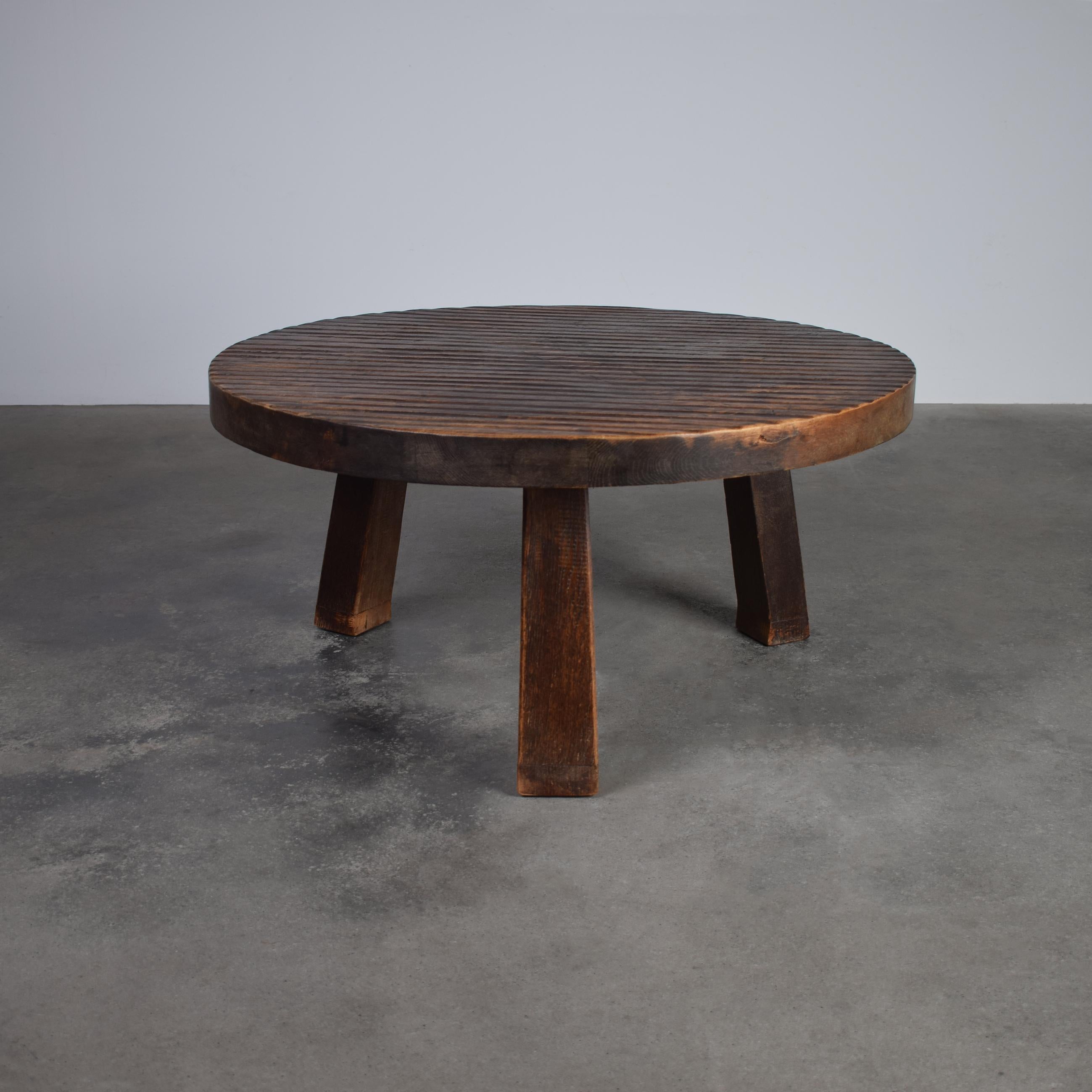 This Mid-Century French Brutalist Round Coffee Table is a stunning example of bold design meeting refined craftsmanship. Made from solid oak, the table features a distinctive ribbed surface that adds texture and visual intrigue. Its round form