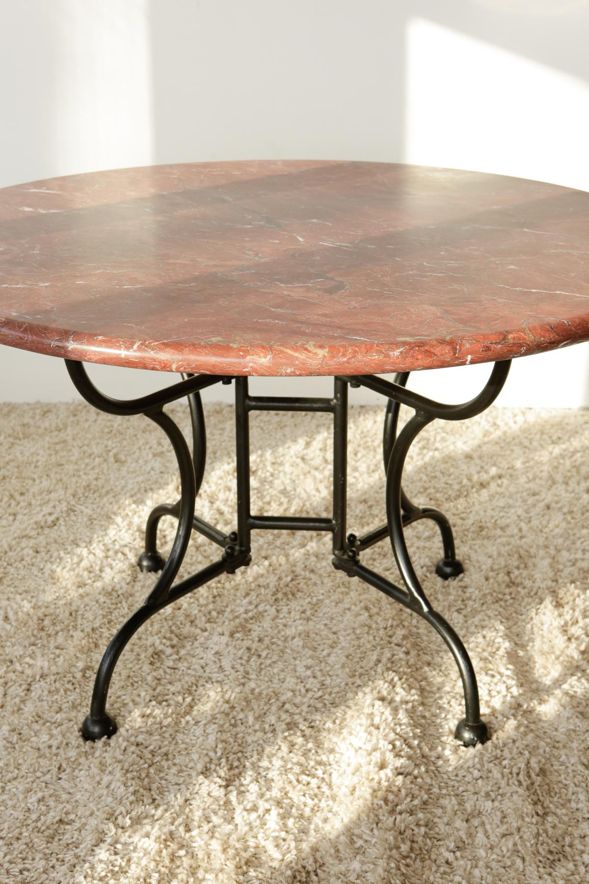 Round burgundy marble table with cast iron legs. One-of-a-kind round table made from a solid burgundy 1.25” thick marble top. The most forgiving color of marble which doesn't get stained or scratched easily. This table brings charming old world