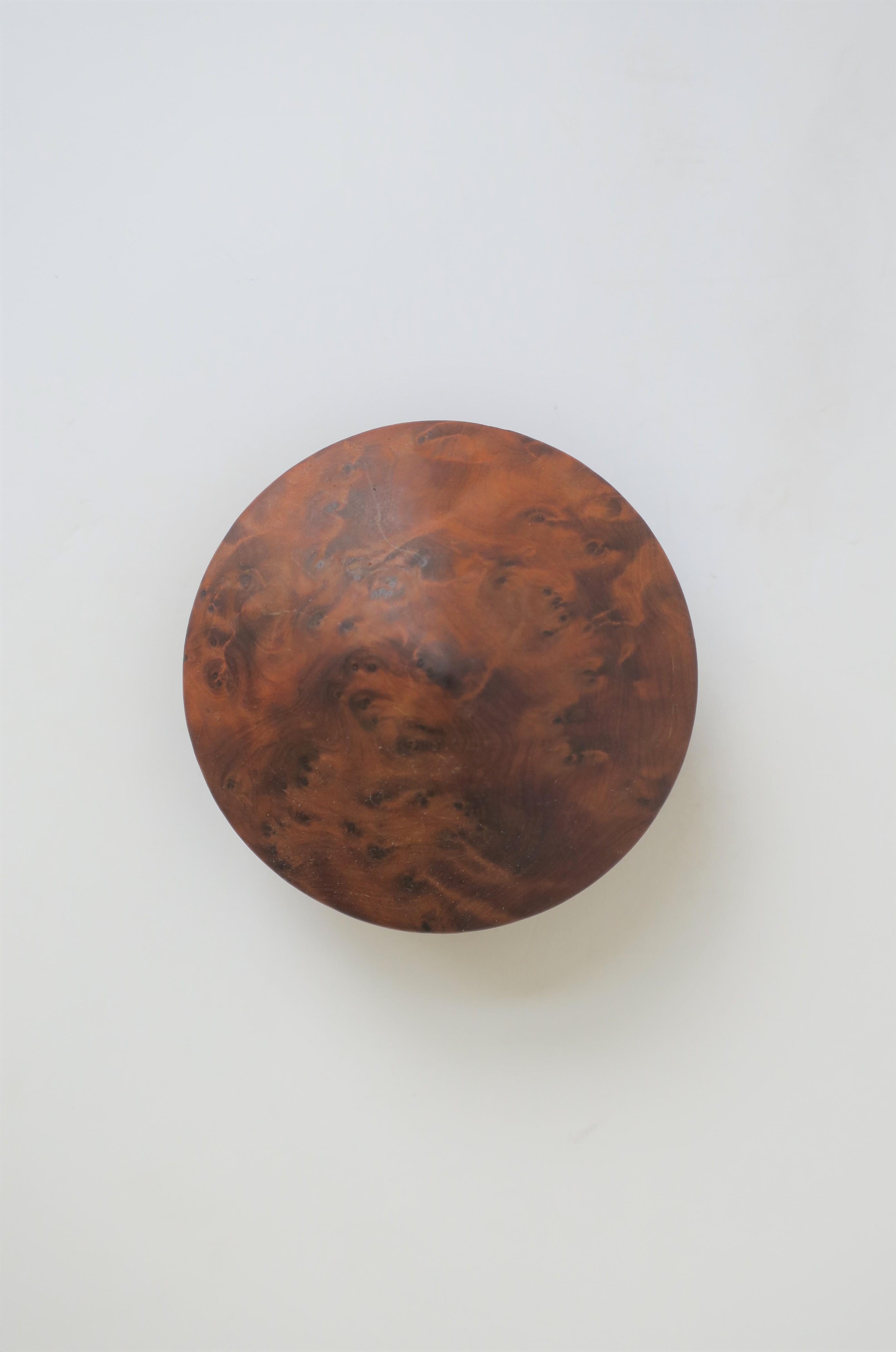 A small round burl wood trinket or jewelry box with pyramid-like top. Perfect for any desk or vanity area to hold small items. Shown with cocktail ring (available separately.) Dimensions: 2.75