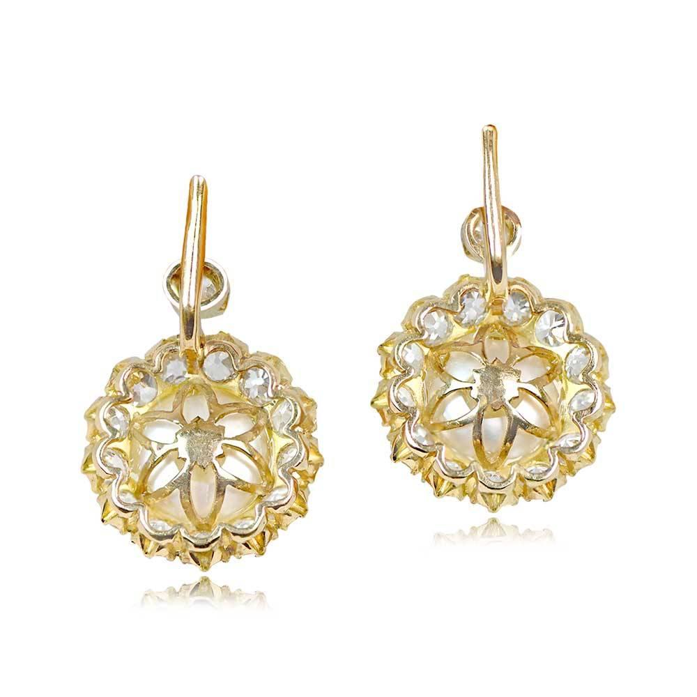 A stunning pair of cluster earrings showcasing two saltwater natural round button pearls weighing 7.89 carats and 8.07 carats. Surrounding the pearls is a cluster of old European cut diamonds with a total weight of 4.80 carats. Crafted in 18k yellow