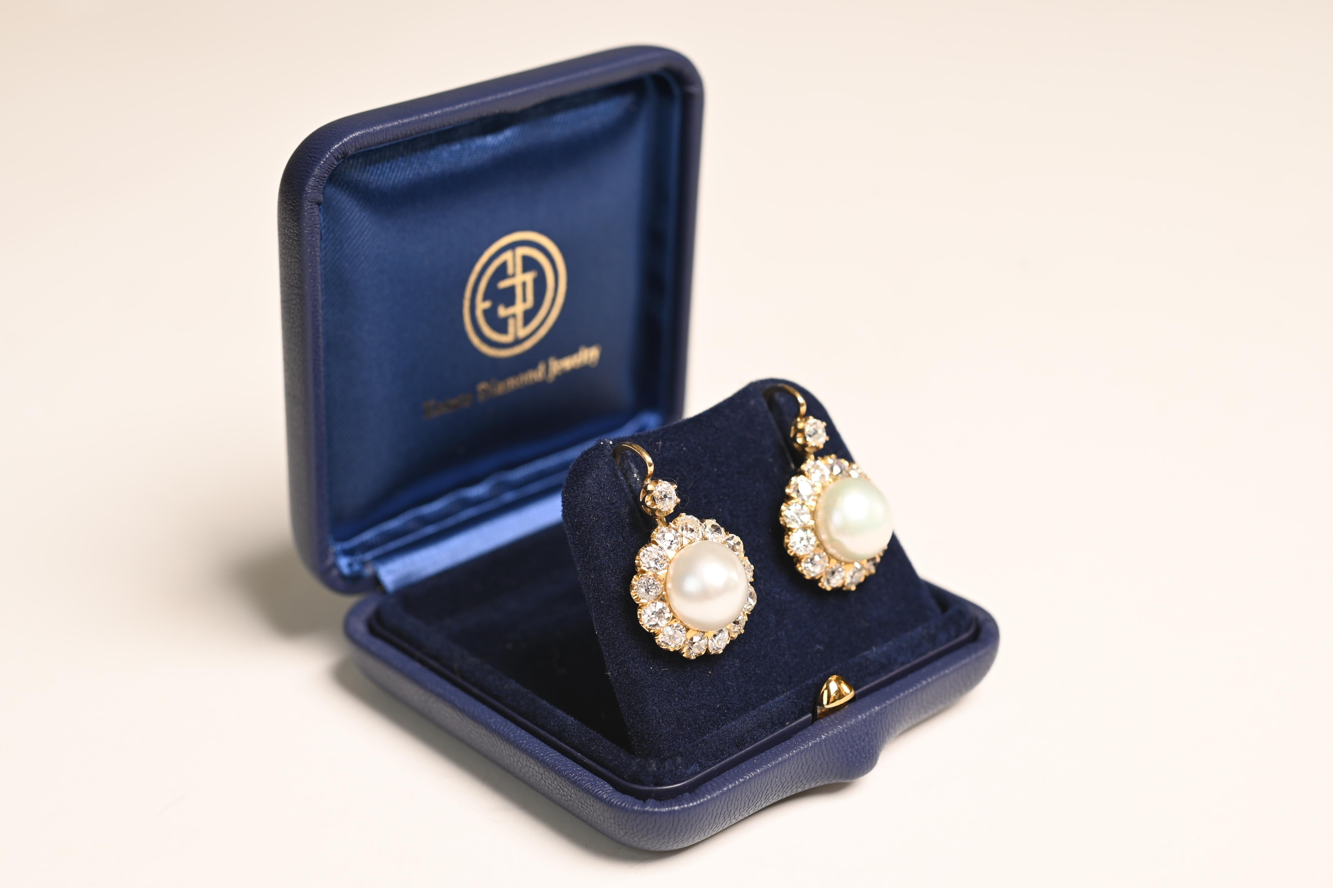 These stunning cluster earrings feature a pair of natural saltwater round button pearls, each weighing approx 7.80-carats and 8.00-carats. The pearls are beautifully encircled by a cluster of exquisite old European cut diamonds, adding a timeless