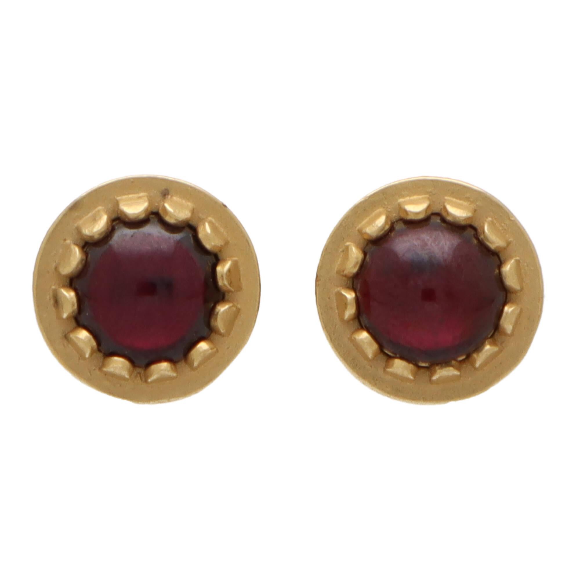  A beautiful pair of round cabochon garnet stud earrings set in 18k yellow gold.

Each earring solely features a vibrant red coloured cabochon garnet, which is claw set to centre. Each stud is secured to reverse with a post and butterfly