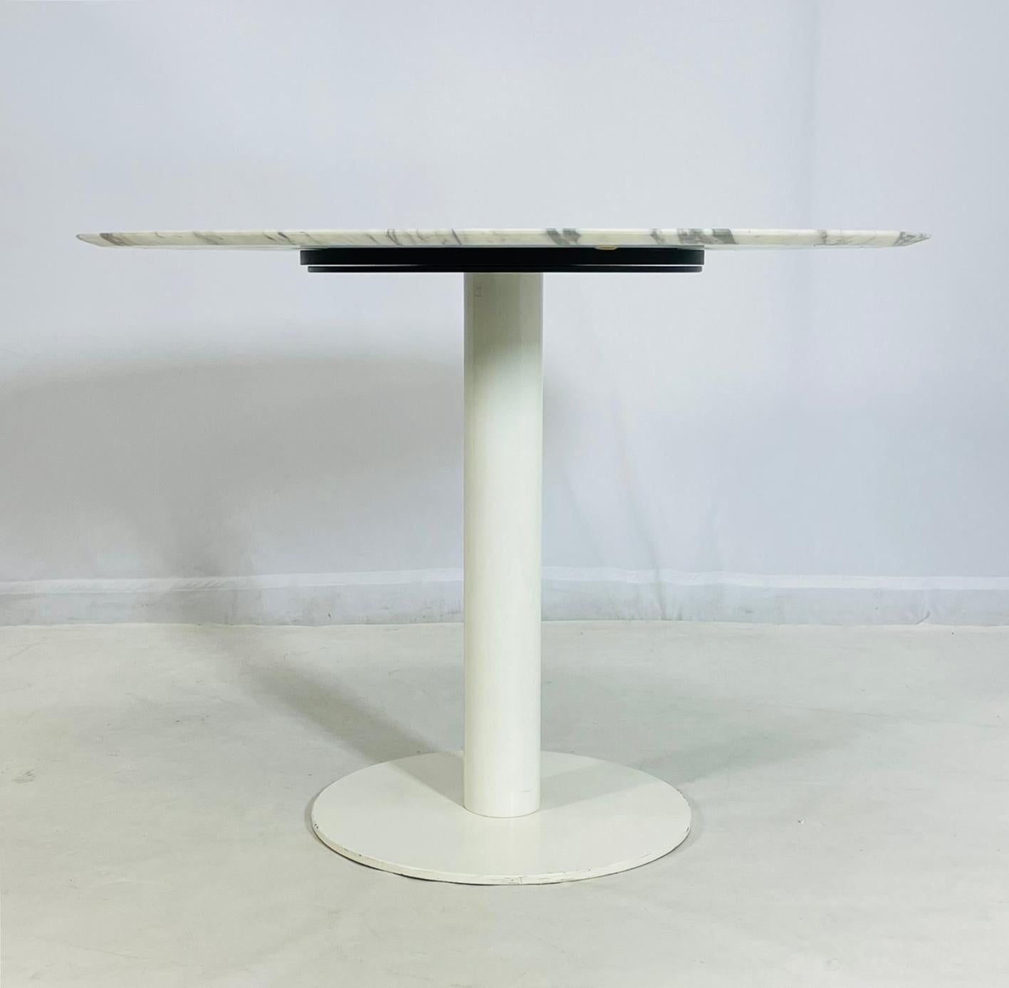 Raffinierter, moderner, runder Esstisch mit einer atemberaubenden Platte aus italienischem Carrara-Marmor mit eleganter grauer Maserung, gepaart mit einem schlanken, weiß pulverbeschichteten Stahlsockel. Mit einem Durchmesser von 41,5 Zoll ist