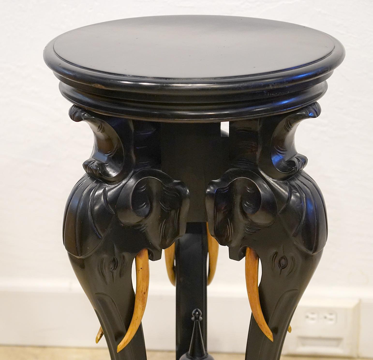 This pedestal by the legendary New York furniture company R. J. Horner and likely dates to the early 20th century. It features three elephant heads with tusks supporting a rotating top all ebonized except for the tusks.