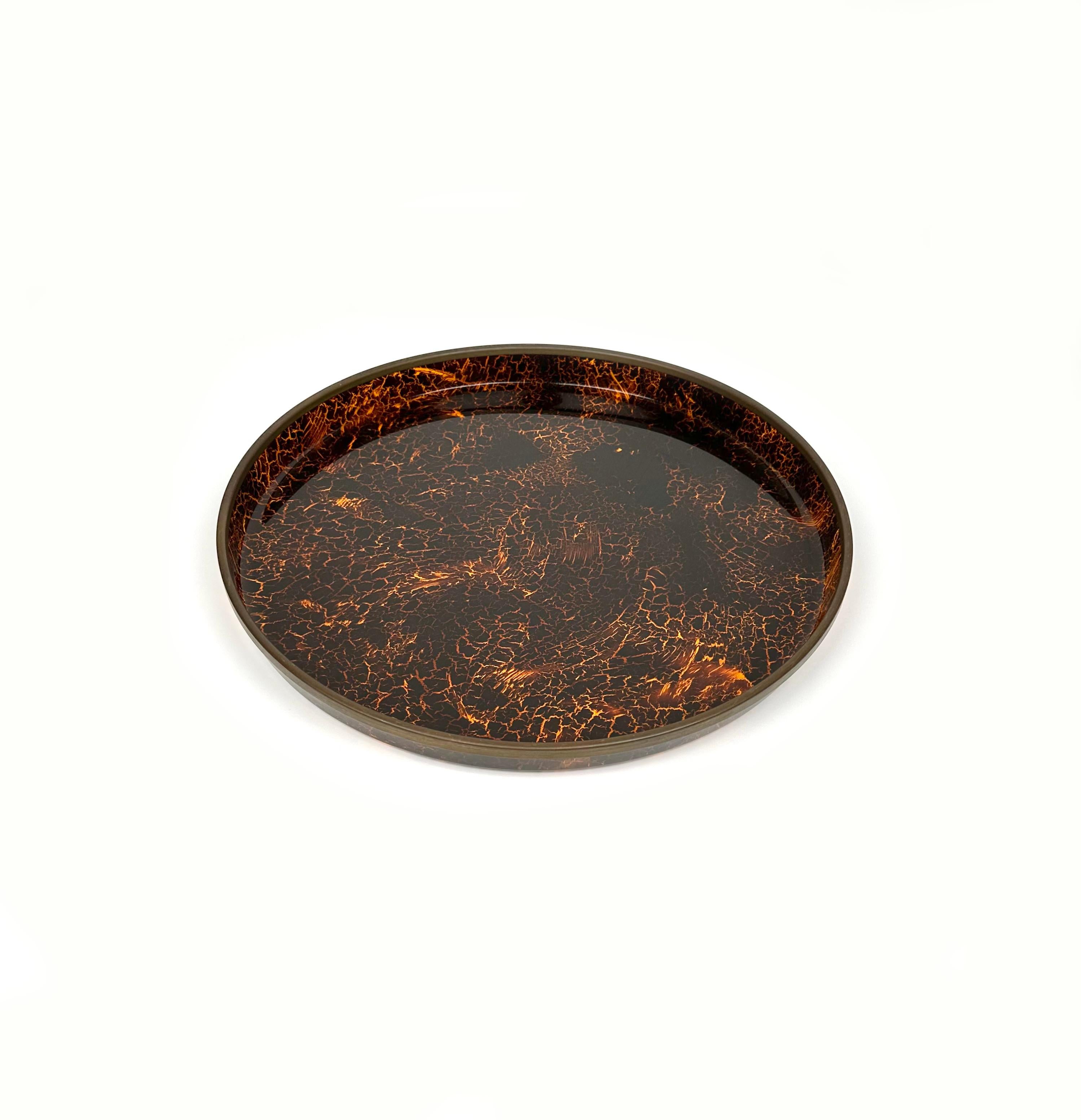 Amazing round serving tray / centerpiece in tortoiseshell effect lucite with and border brass in the style of Christian Dior.

Made in Italy in the 1970s.