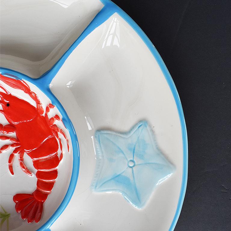 Round circular Lobster food platter. With three compartments for chips, dips or Crudités, this serving platter will be a welcome accompaniment to any party. The center features a red lobster, and each compartment features a raised shell motif. The
