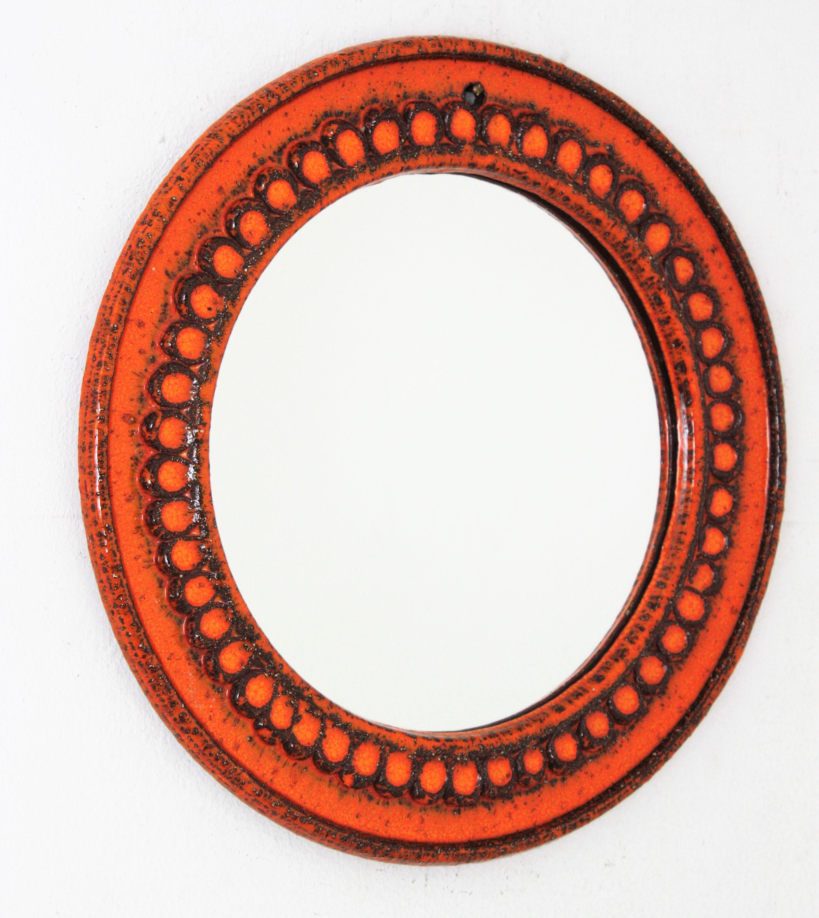 Round wall mirror by Villeroy Boch in orange glazed terracota, Germany, 1960s-1970s
German Midcentury-Modern orange terracotta glazed ceramic circular mirror with geometric pattern surrounding the glass.
This mirror will be a colorful midcentury