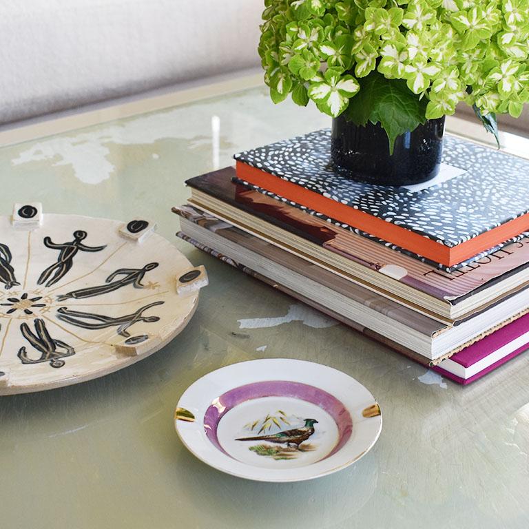 A small pink and gold ceramic ashtray or vide poche with a bird motif. A lovely decorative trinket dish or ashtray that will be gorgeous on a side table or dressing table. The porcelain dish is round and is hand-painted with a metallic pink border