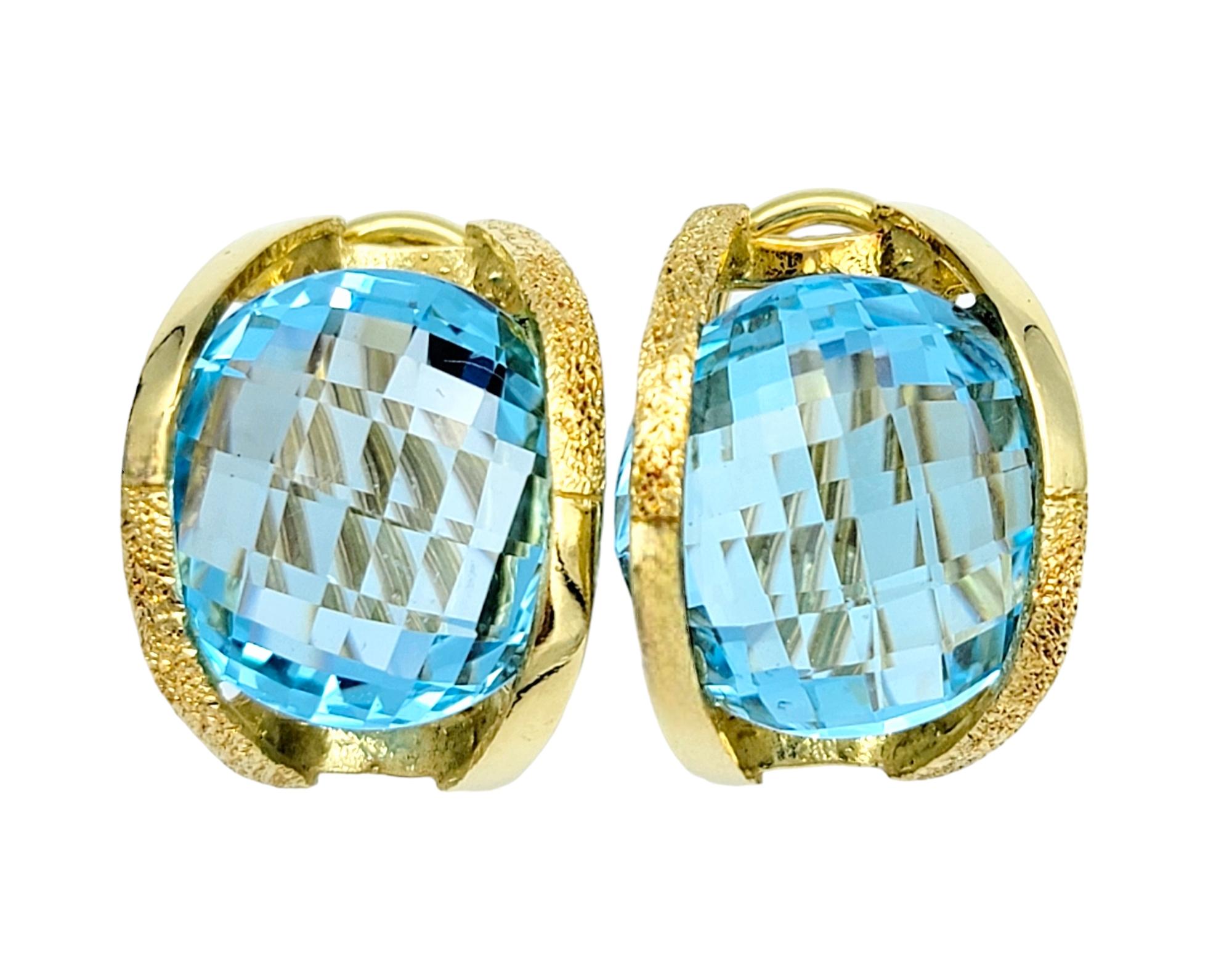 These round blue topaz earrings, set in lustrous 18 karat yellow gold, are an elegant piece of art. Each earring features a captivating blue topaz gemstone that glimmers with ethereal hues reminiscent of a tropical ocean. The gemstones are expertly