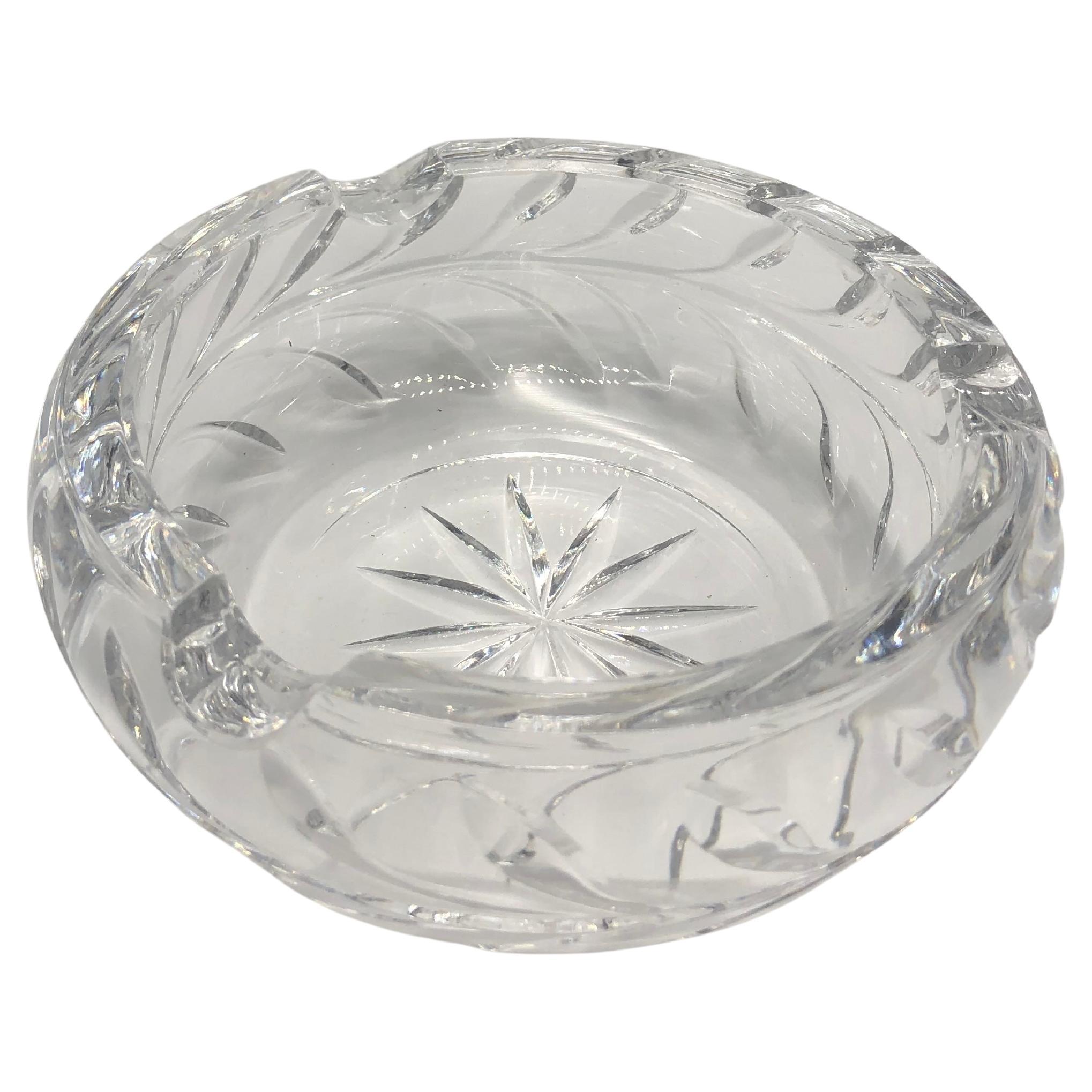 Clear, thick, unmarked, round, crystal-cut glass ashtray in perfect condition. 

It has a star/sunburst cut motif in the center with leaf-cut design detail around the edges. 

It is a pretty decorative tabletop piece that can also be used as a