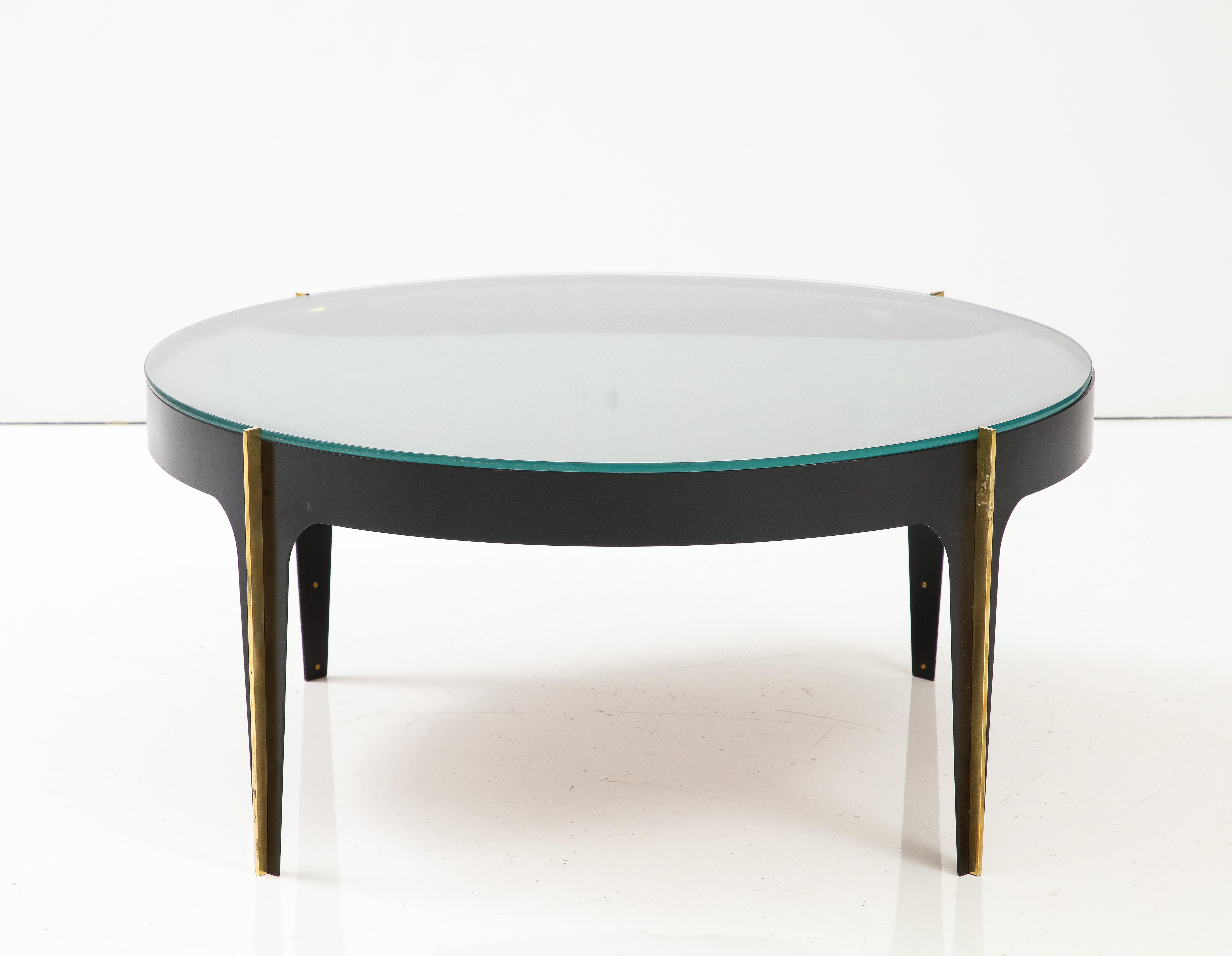 Iconic round cocktail table attributed to renowned French designer Max Ingrand for Fontana Arte Model 1774, Italy, late 1960s. The cocktail table consists of a round structure in black enameled metal with vertical solid brass inserts on the legs.