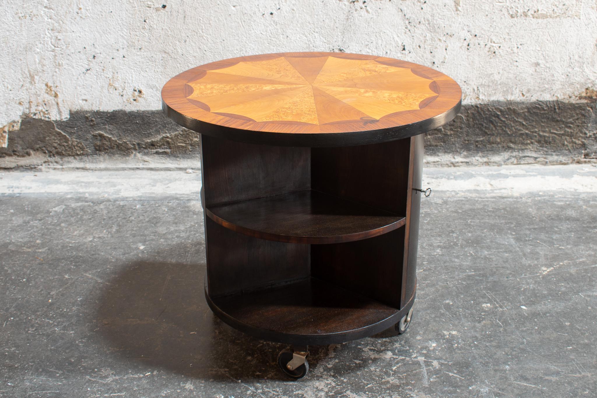 Unique Birch coffee/bar table on casters with stunning inlay tabletop. Inlay includes jacaranda, burl elm, and rosewood. Table has two sets of shelves, and a cabinet door with lock. There is a small mark on the top of the table (pictured) that was