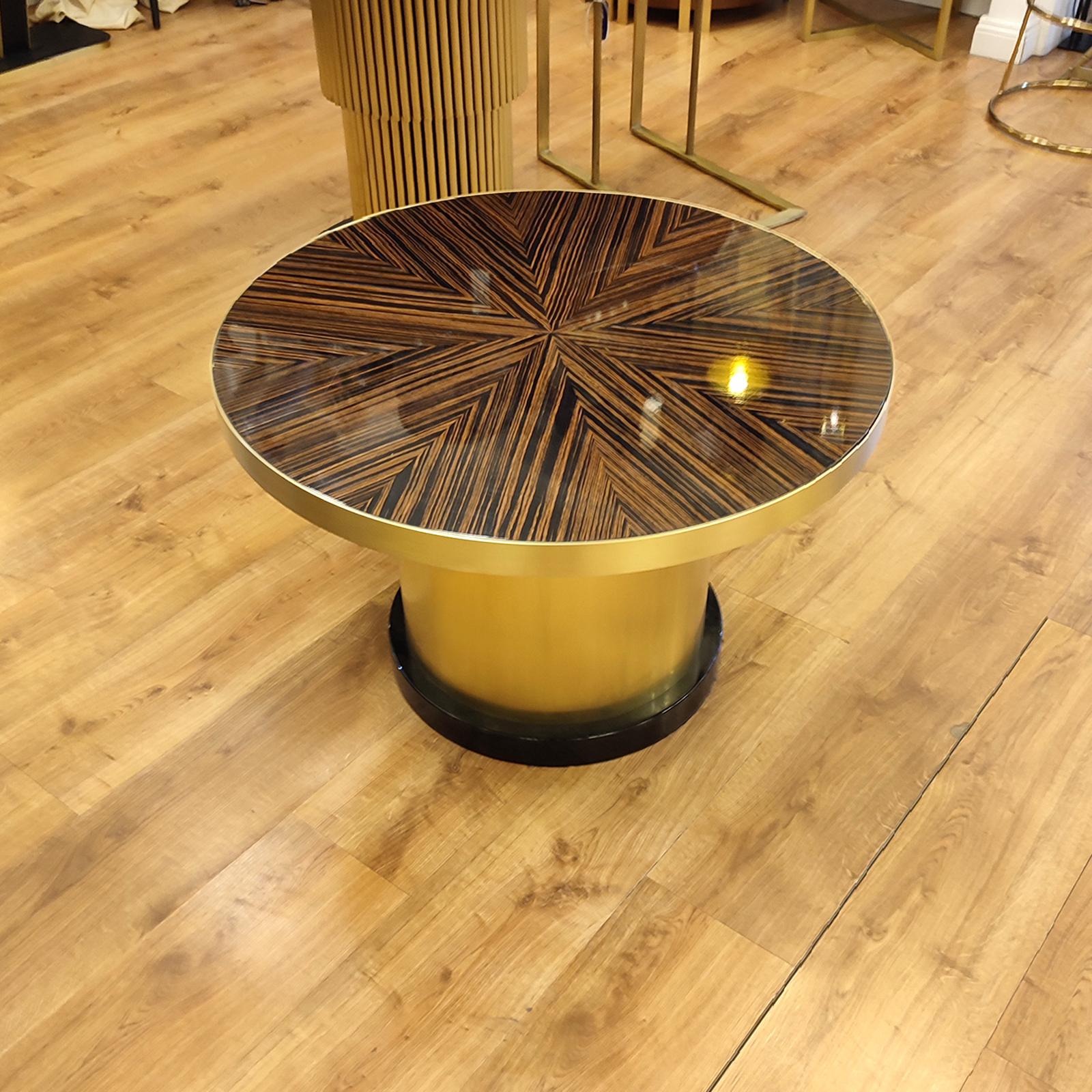 Art Deco Style round coffee or cocktail table, made of a brushed foot brass, with MDF top and base. Top decorated in makassar star look, high glossy lacquer finish. 
Dimensions: diameter 76 cm, height 49 cm.
New and made to order, one piece