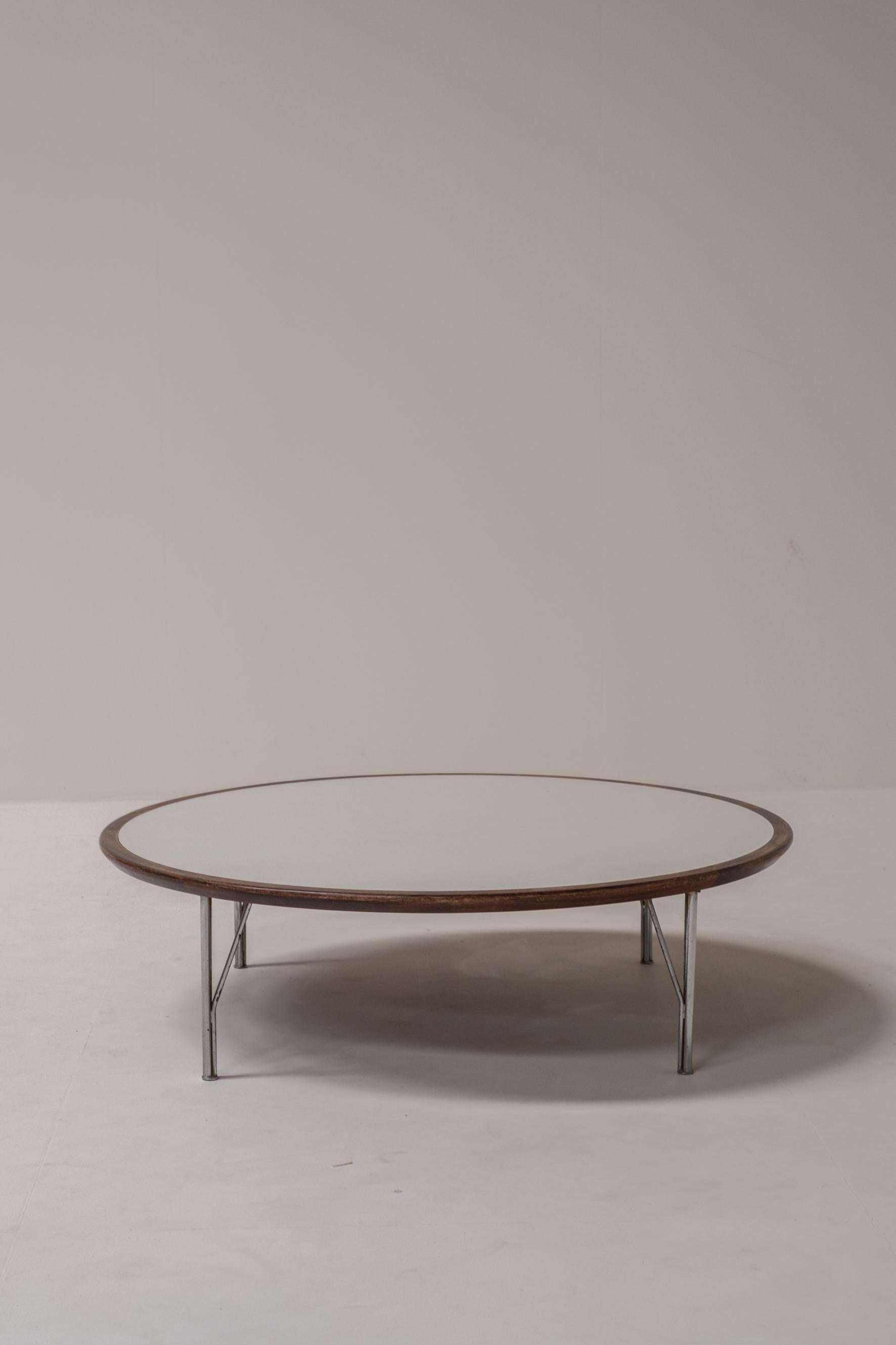 Table basse ronde élégante du milieu du siècle, présentant une combinaison raffinée de matériaux : un bord en bois foncé, un plateau en stratifié blanc et des pieds élancés en acier chromé. Sa construction minimaliste et ses proportions légères lui