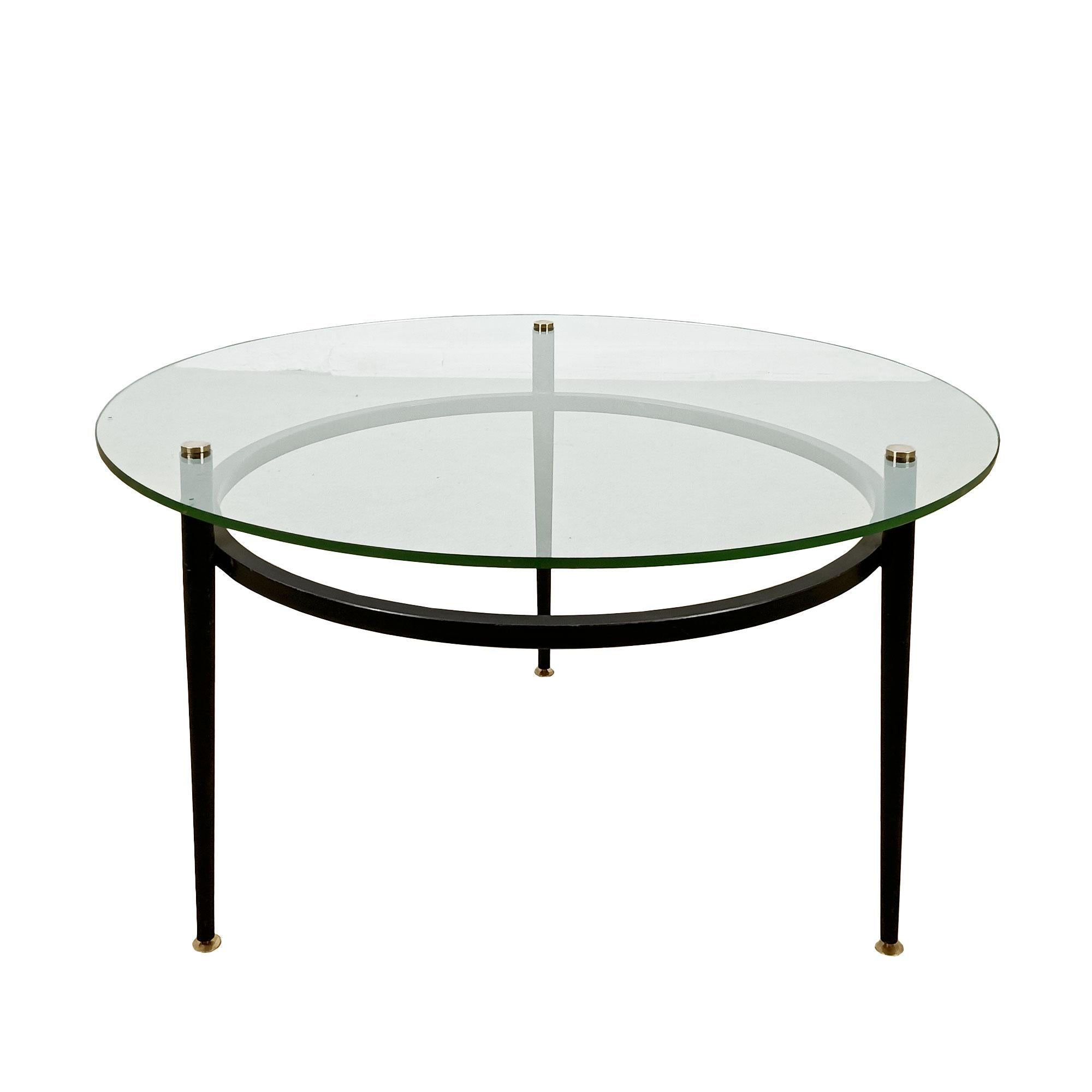 Table basse ronde à structure en acier noirci reposant sur de petits pieds en laiton, épais verre d'origine percé maintenu par trois vis à tête plate en laiton poli.

France circa 1950