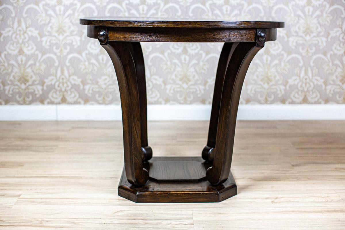 We present you a coffee table made of oak wood and veneer.
The whole is from the Interwar Period.
The round table top is supported on four slightly bent legs, which are placed on a square base with cut corners.

This piece of furniture has
