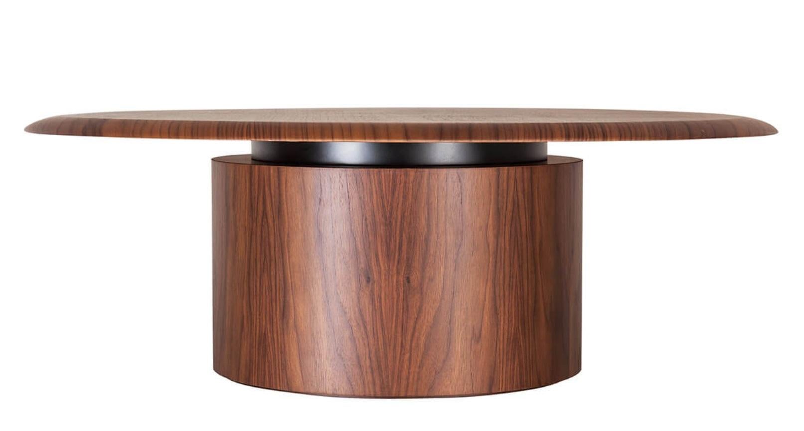 The low table features a round, curved plywood base and a beveled wooden top. It is available in different woods and lacquers, offering a customizable design to suit various interior styles. This piece combines minimalist aesthetics with functional