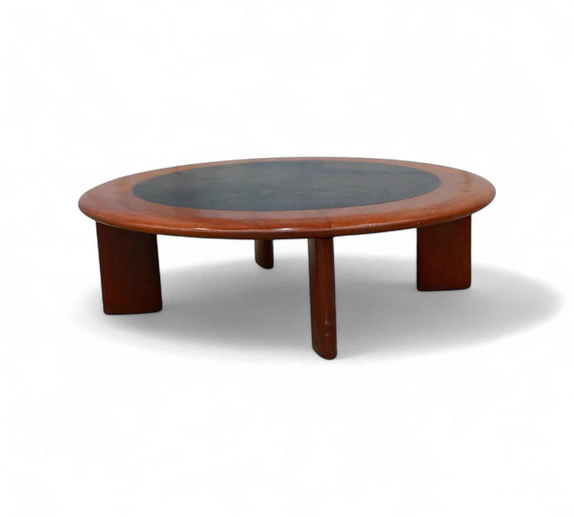 Cette table basse ronde est fabriquée en bois dur et recouverte de cuir noir. Il se compose d'un plateau circulaire soutenu par quatre pieds délicatement incurvés. Le bois a été remis à neuf pour améliorer son apparence, tandis que le dessus en cuir