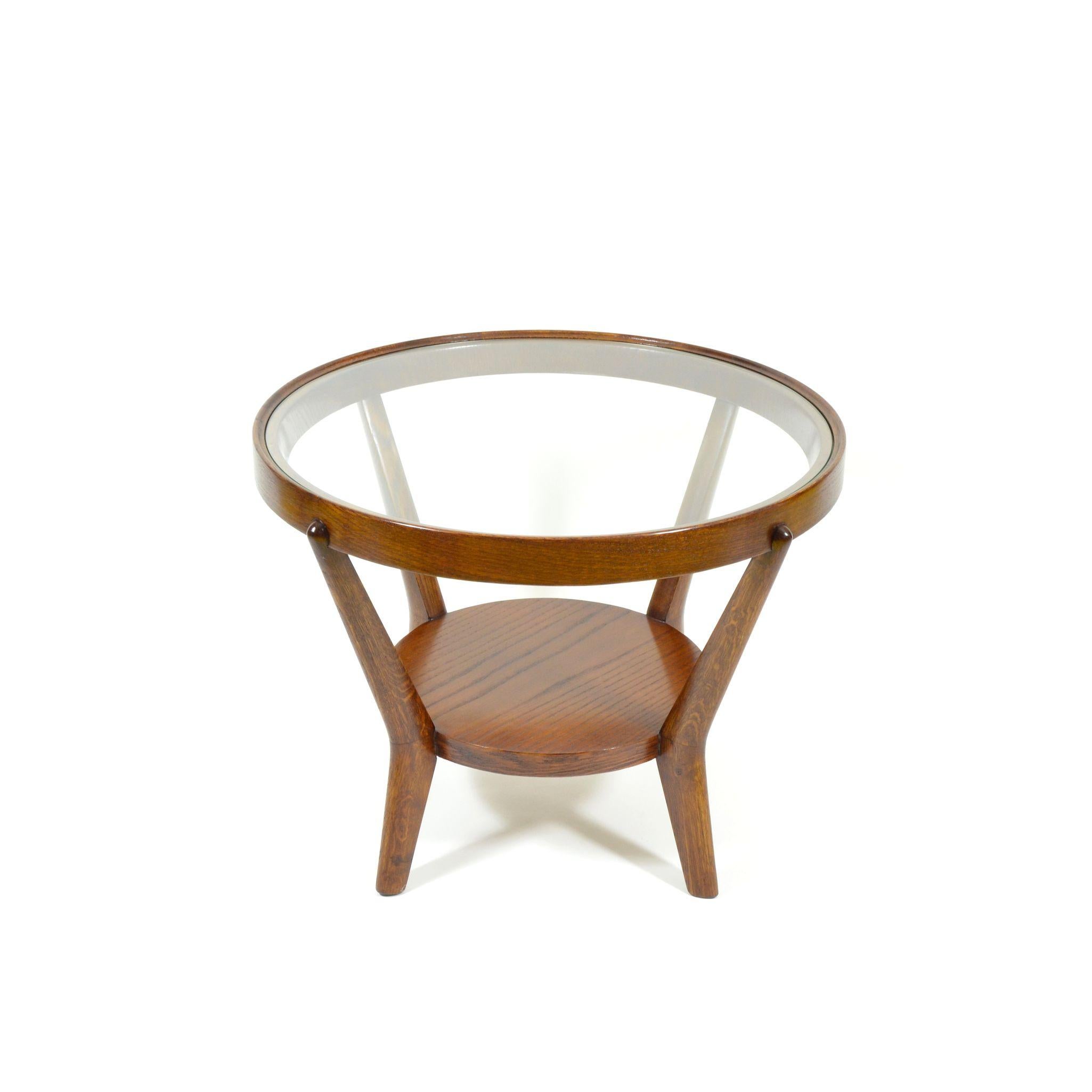 Round coffee table in functionalist style, designed in 1944 by K. Koželka and A. Kropácek for Ceské Umelecké Dílny. Varnished veneer, round glass table top inserted into a wooden frame. This table comes from a seating group that won a silver medal