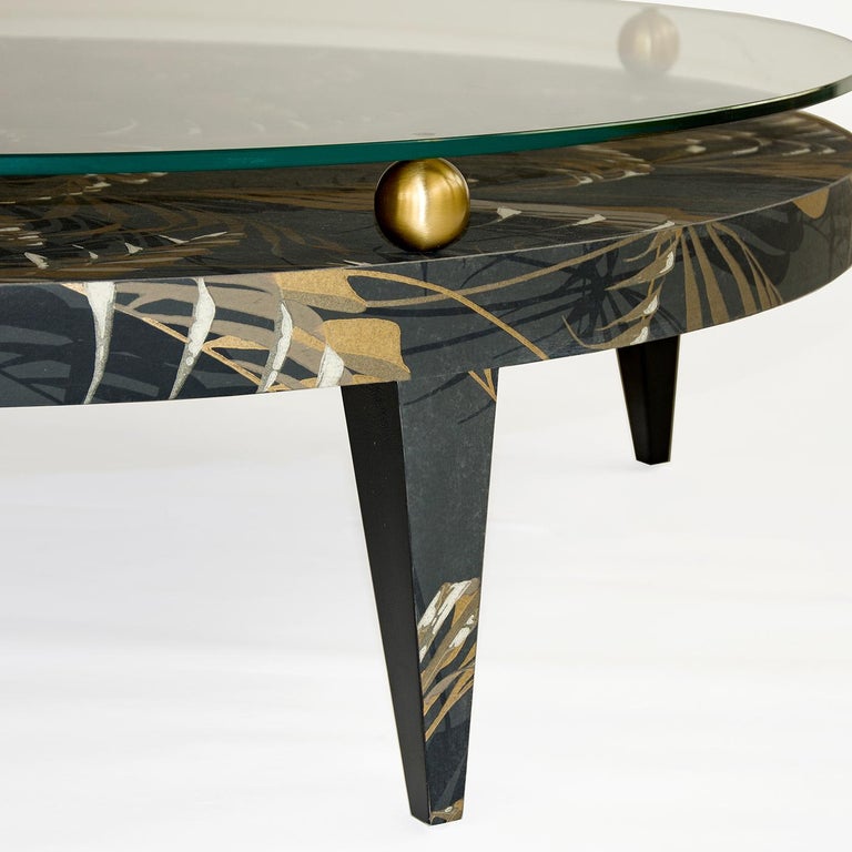 Perfect to complete a sophisticated living room or to give a touch of style and originality to a sober and minimal interior. This coffee table is made of wood and uphpolstered with wallpaper. The upper round top is made of glass, spaced and placed