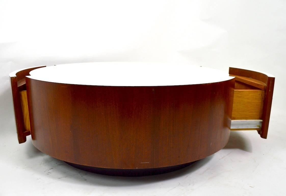 Disk form coffee table with textured white formic top, veneer sides, and two deep storage drawers. We believe this was a custom-made item, circa 1970s. This example shows some cosmetic wear, scuffing at the sides, normal and consistent with