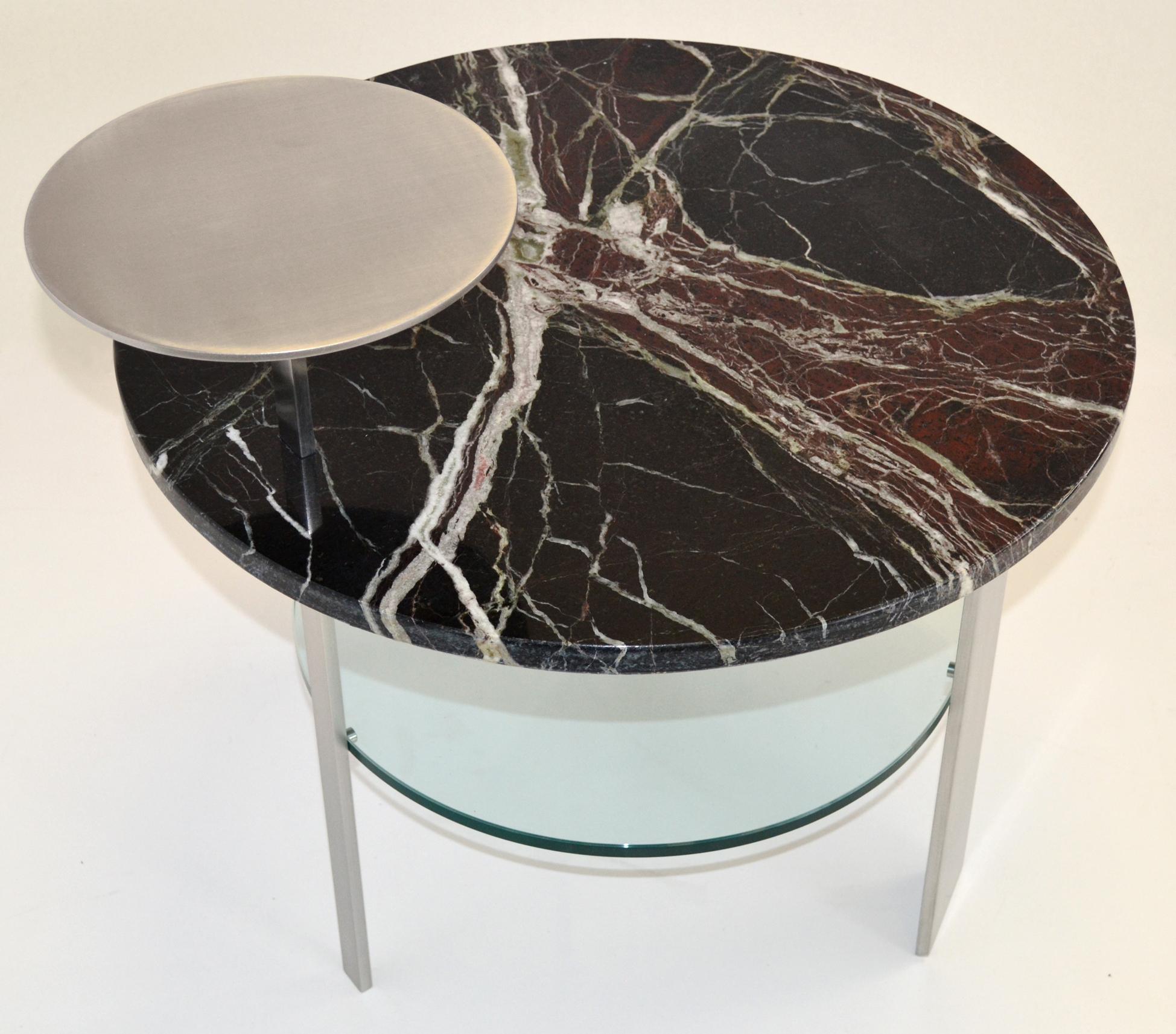 This art deco style stunning table is handcrafted using three kind of materials as satin-finished stainless steel for the three legs and higher top, Red Levanto Italian marble and glass for the lower top. 
The table has a functional use, based on