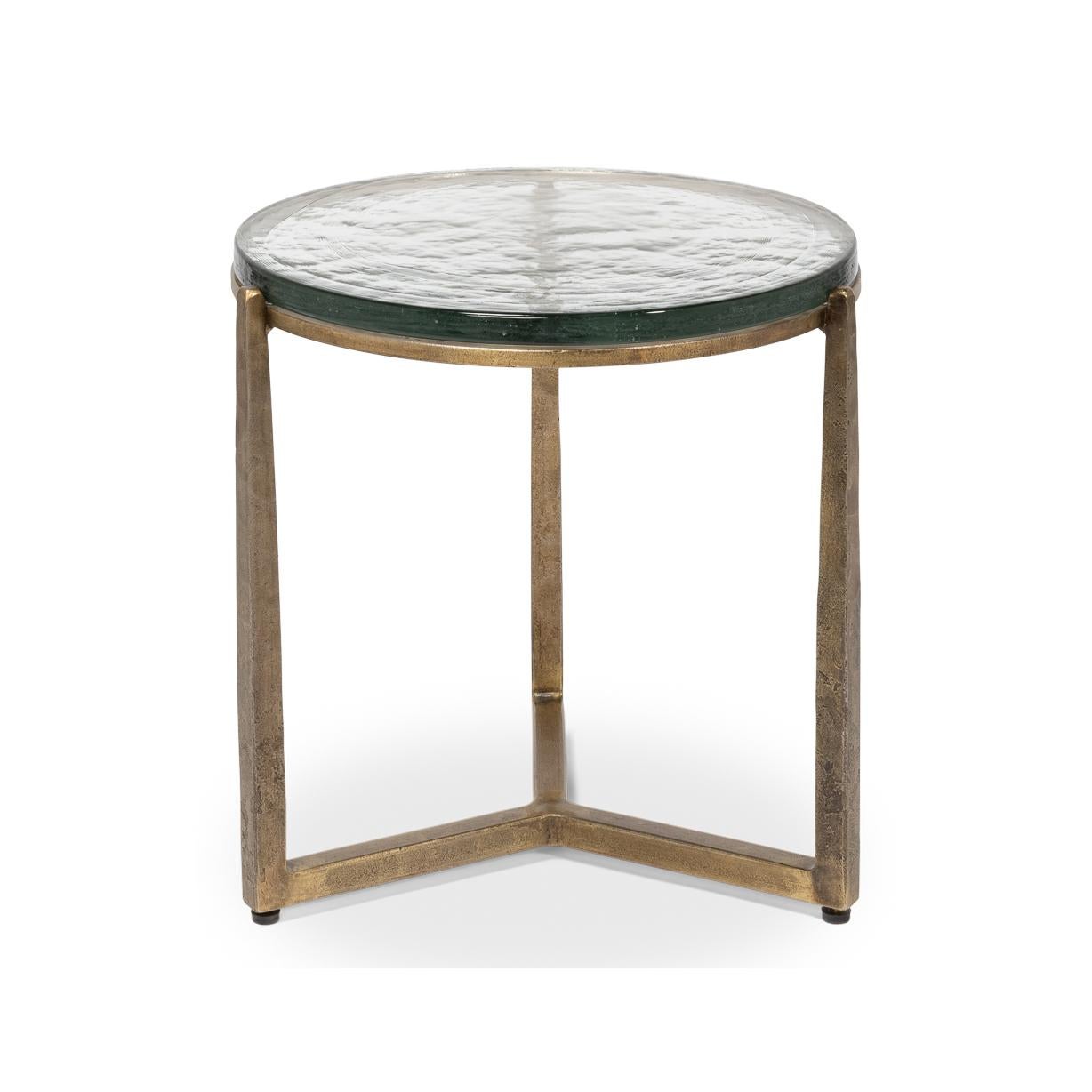 Dieses exquisite Stück verfügt über einen handgeschmiedeten Eisensockel in gealterter Messingausführung, der einen Hauch von Vintage-Eleganz vermittelt und gleichzeitig eine schlichte, moderne Ästhetik bewahrt. Die Gussglasplatte mit ihrer
