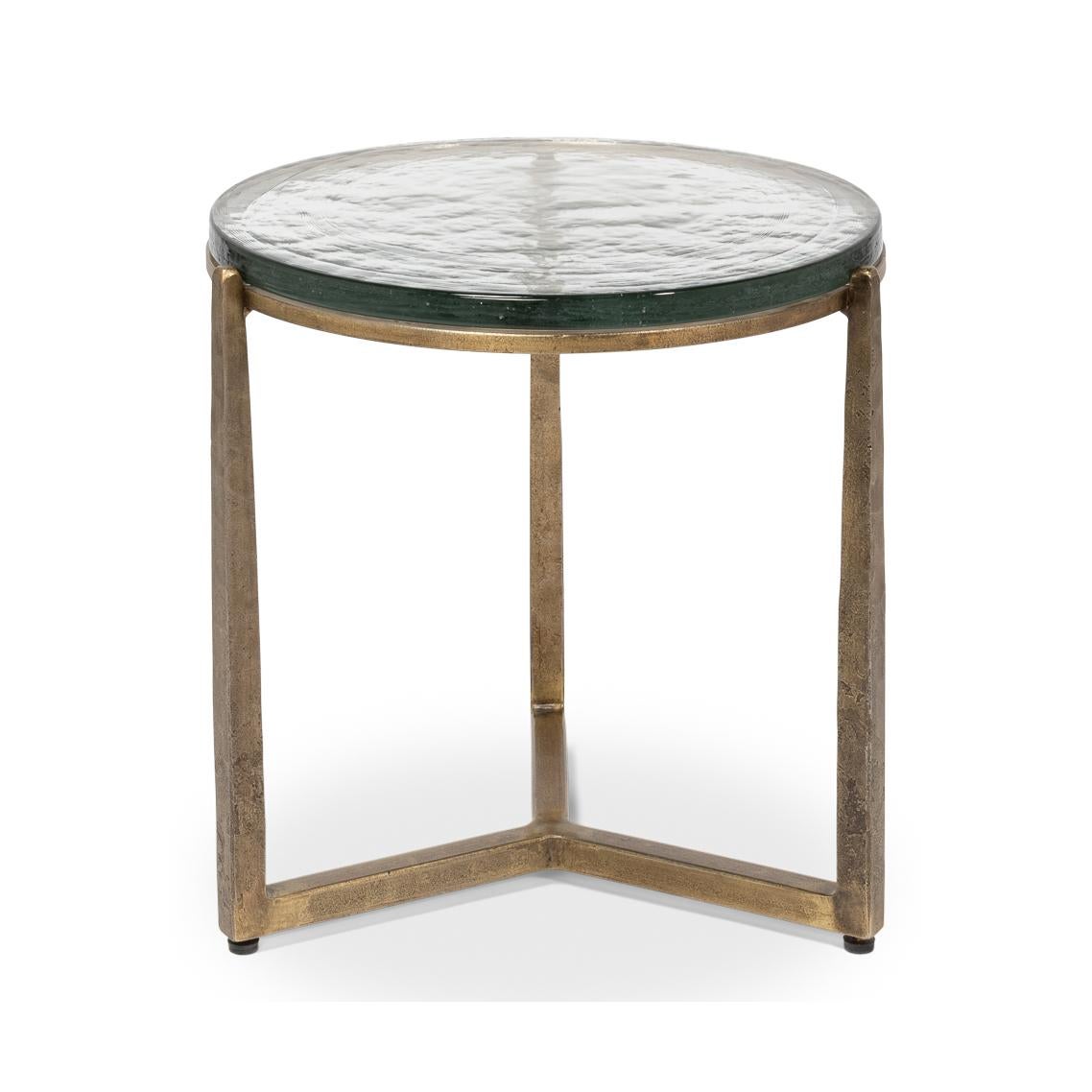 Dieses exquisite Stück verfügt über einen handgeschmiedeten Eisensockel in gealterter Messingausführung, der einen Hauch von Vintage-Eleganz vermittelt und gleichzeitig eine schlichte, moderne Ästhetik bewahrt. Die Gussglasplatte mit ihrer