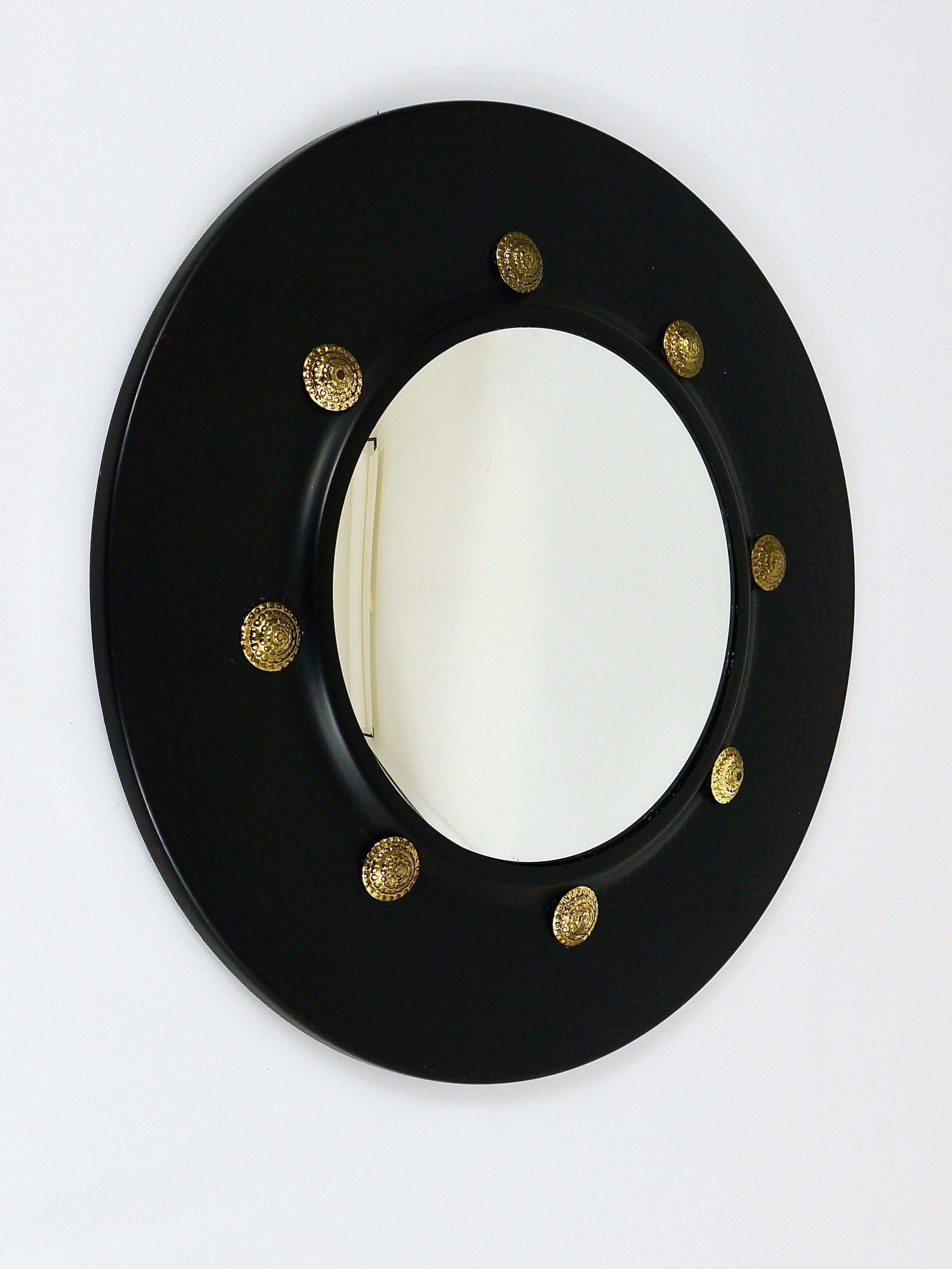 A very beautiful round wall mirror with convex mirror glass from the 1960s, made in Italy. In the style of Piero Fornasetti. The frame is made of black-finished 