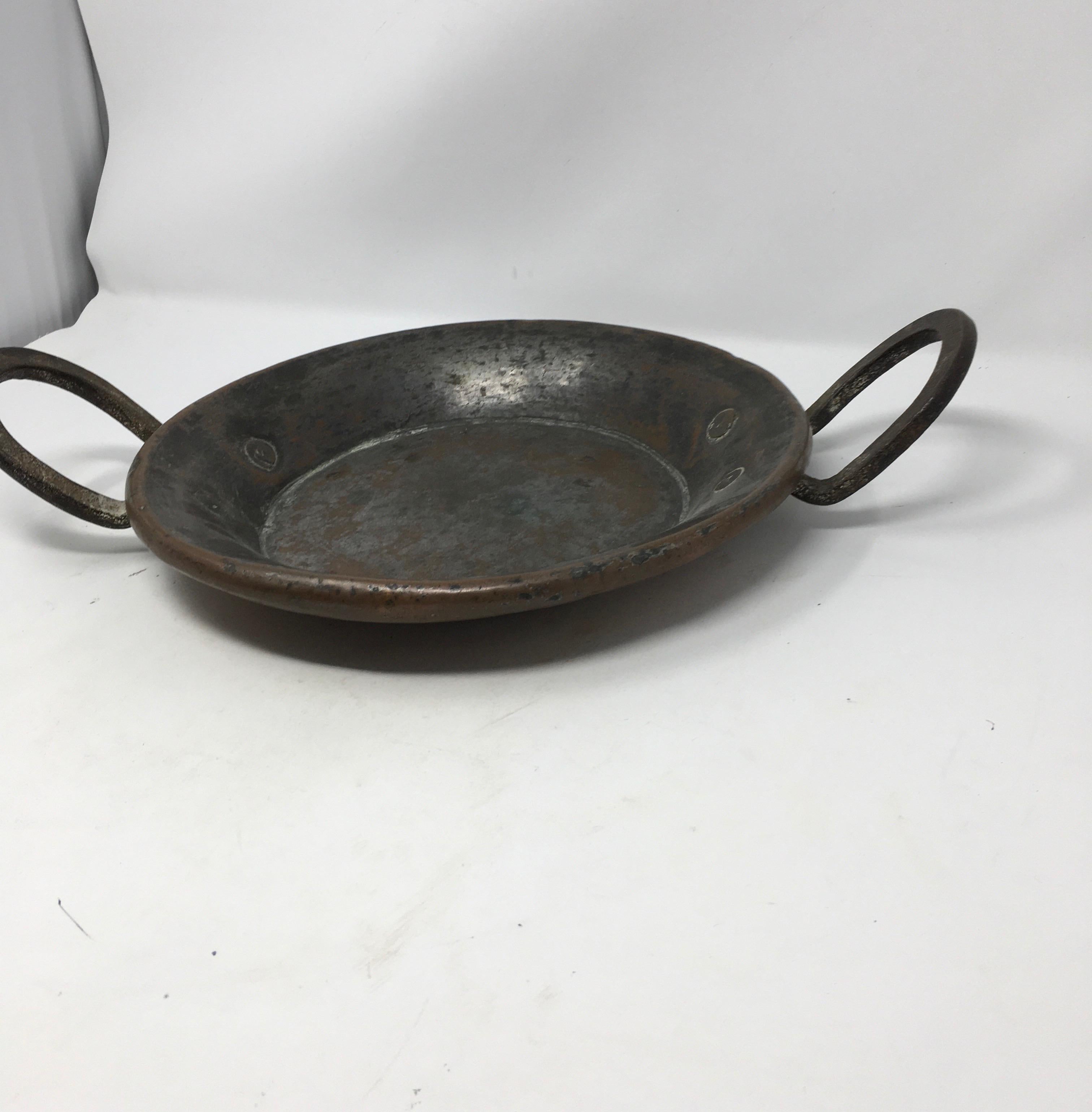 Si tratta di un'antica pentola francese in rame con manici in ferro e rivetti in rame. La pentola è rivestita di stagno, ma ha perso un po' di stagno in molti anni di utilizzo. Con una splendida patina, questo pezzo aggiunge un fascino provinciale