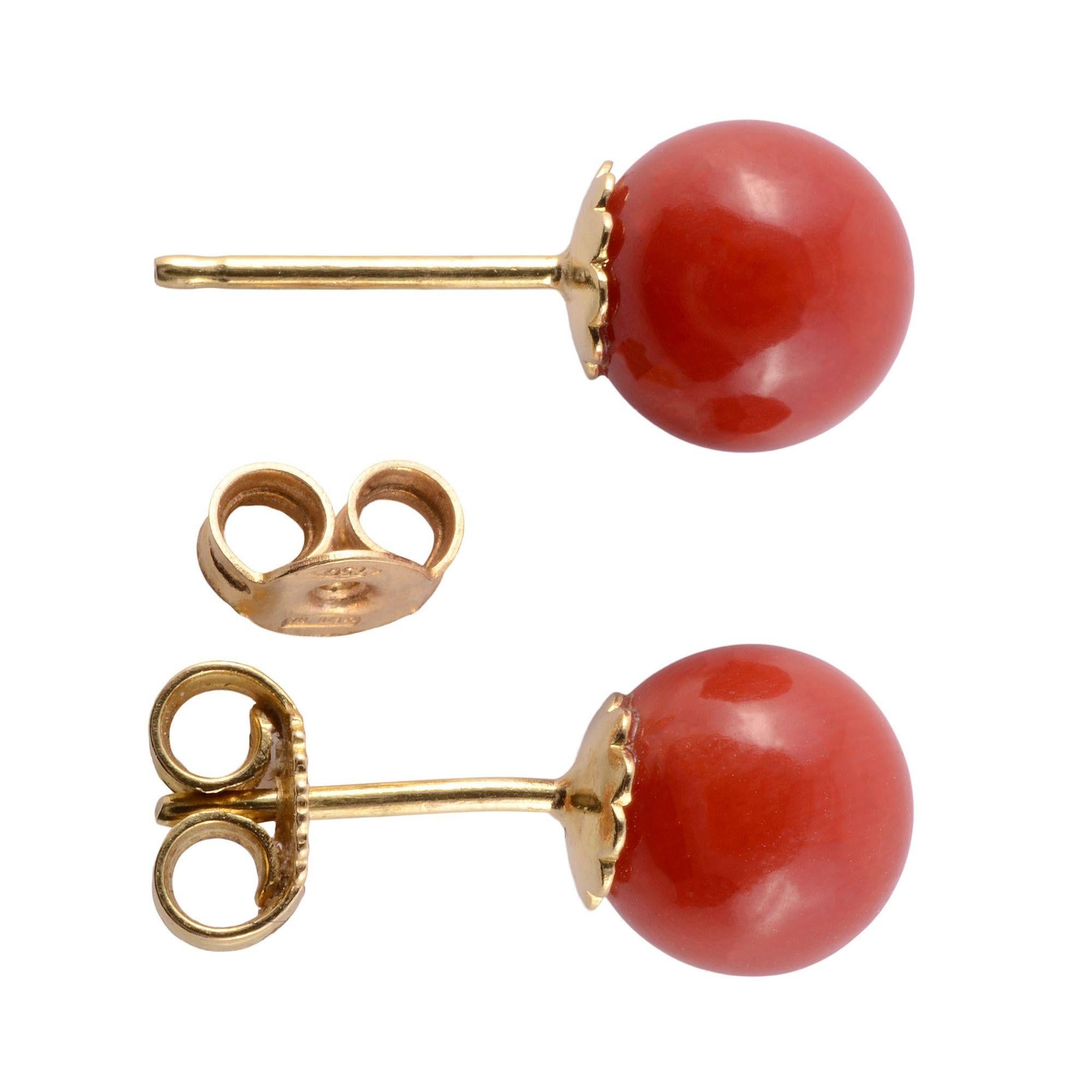 Estate round coral stud earrings. These coral earrings feature 18 karat yellow gold posts and backs. The coral measures 7.5mm diameter. [KIMH 426]