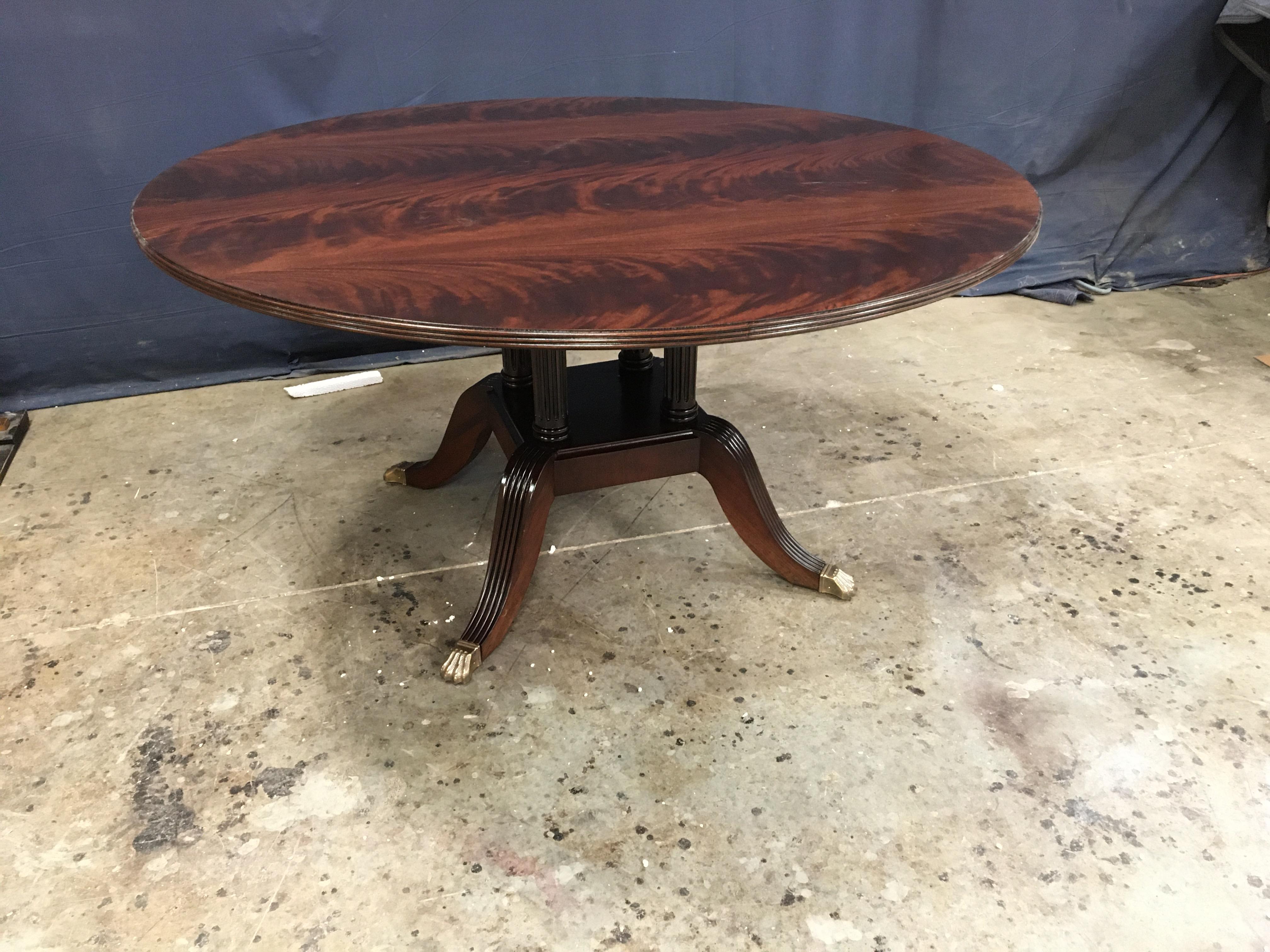 This is made-to-order round traditional mahogany dining table made in the Leighton Hall shop. It features a field of reverse-slip-matched West African swirly crotch mahogany which gives the table top unique character. It has a solid mahogany three