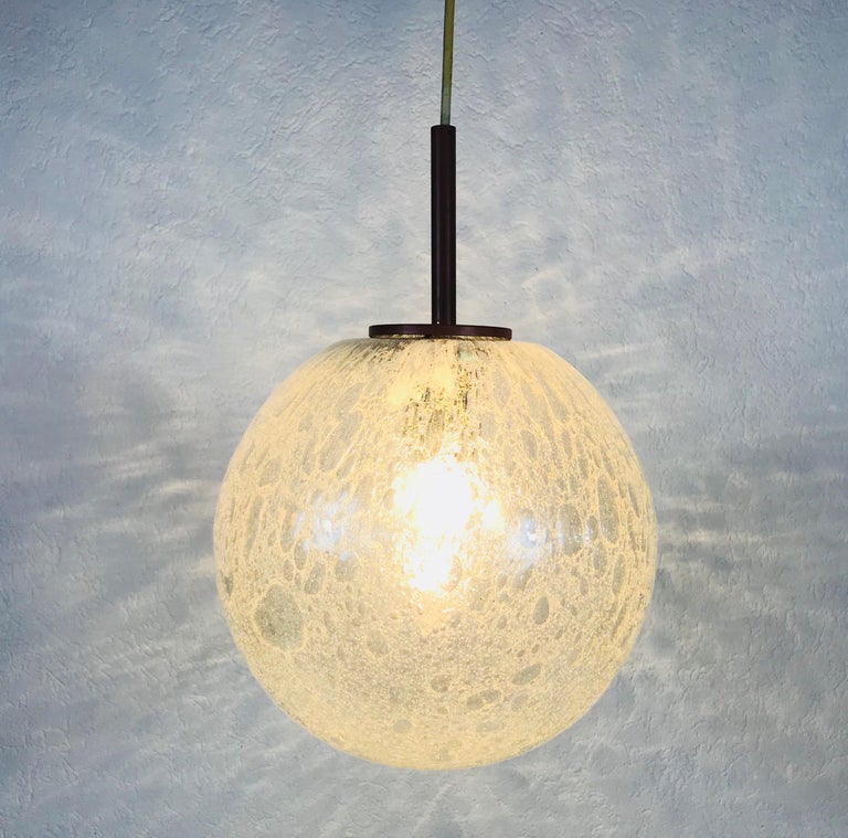 A beautiful glass bowl hanging lamp made in Germany in the 1970s. The light is made of Murano glass. It has an amazing transparent color and it is very solid. The top of the lamp is pink colored metal.

The light requires one E27 light bulb.