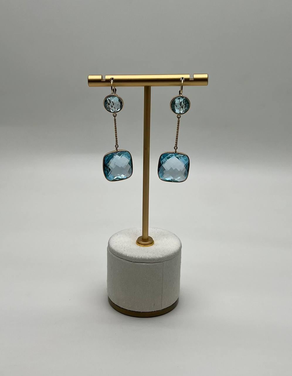 Descubre la elegancia de nuestros exquisitos pendientes de gota, elaborados con precisión y arte.

Estos cautivadores pendientes presentan una armoniosa mezcla de oro de 14 quilates y asombrosos topacios azules. El diseño presenta un delicado