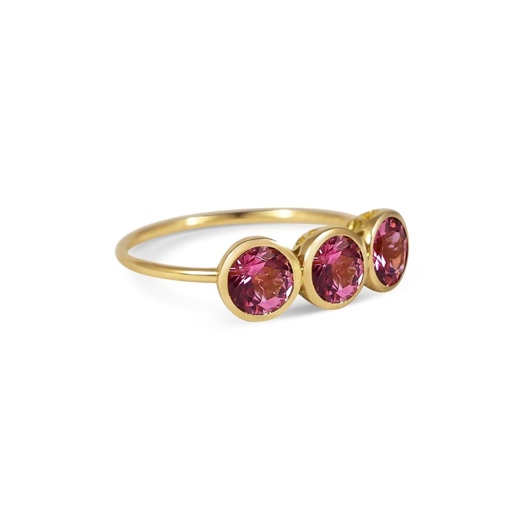 Handcrafted Round Cut 1.50 Carats Pink Tourmalines 18 Karat Yellow Gold Three-Stone Ring. This classic three-stone or trilogy ring features round brilliant cut stones set in a rub over setting on a simple band. The 6mm natural Pink Tourmaline stones