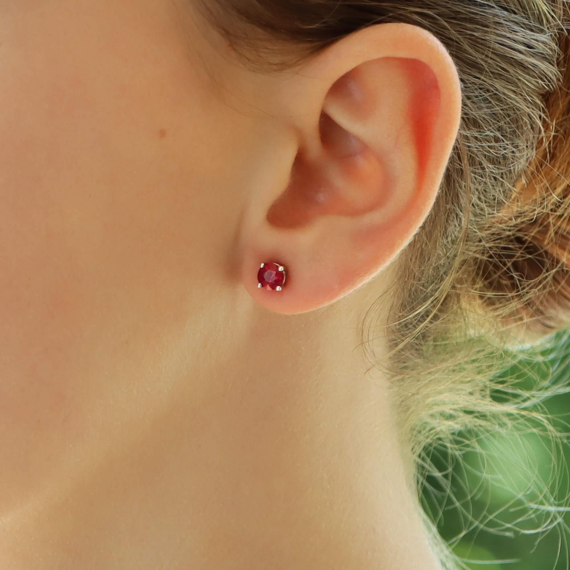  A beautiful pair of round cut vibrant ruby stud earrings set in 18k white and yellow gold.

Each earring solely features a sparkly red colored round cut ruby, which is four claw set to center. Each stud is set in an open back setting and are