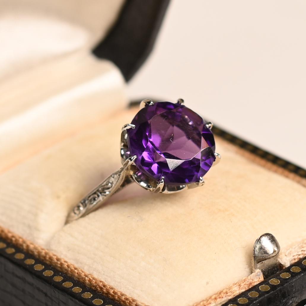 Questo anello antico e raffinato mette in mostra una splendida ametista di circa 3,20 carati con taglio rotondo, incastonata in un'elegante montatura a otto punte. La tonalità viola intenso della gemma riflette la raffinatezza senza tempo dell'epoca