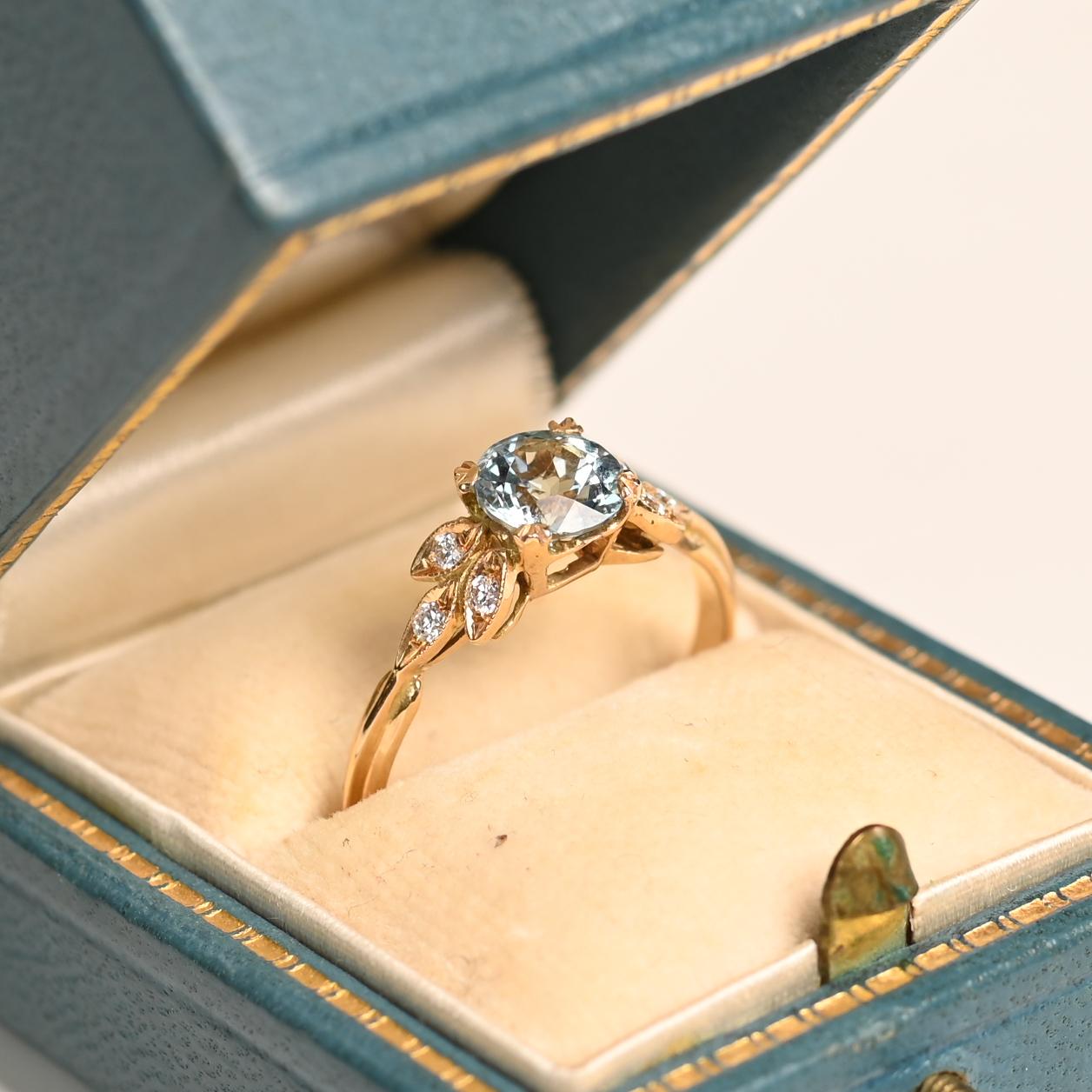 Este exquisito anillo de compromiso de oro amarillo de 18 quilates exhibe una cautivadora aguamarina redonda de 6 mm, firmemente engastada en delicadas garras. La aguamarina, con un peso aproximado de 0,70 quilates, exhibe un hipnotizante tono azul