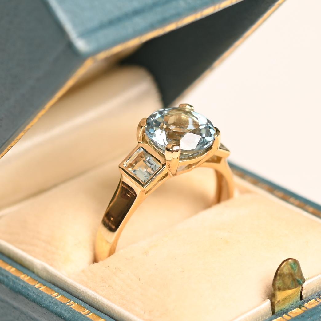 Este exquisito anillo de aguamarina exhibe en su centro una fascinante aguamarina de talla redonda, con un peso aproximado de 1,9 quilates. El tono azul brillante de la gema se complementa con los expertos engastes de las garras, que permiten que la