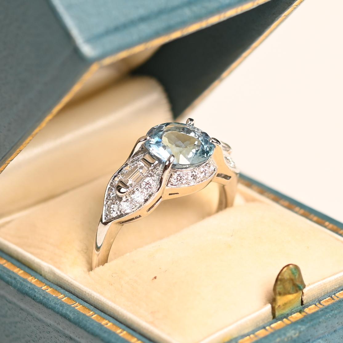 Questo squisito anello con acquamarina mette in mostra una splendida acquamarina rotonda di circa 1,70 carati, elegantemente incastonata in rebbi. La vibrante pietra centrale è completata da eleganti spalle geometriche ornate da diamanti a baguette