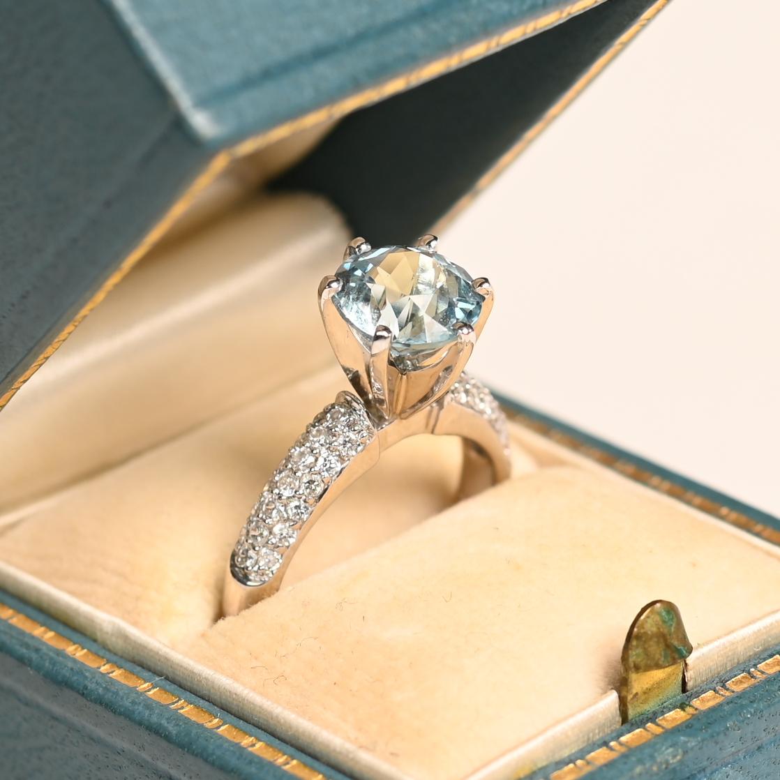 Cette bague exquise met en valeur une aigue-marine de taille ronde d'environ 1,80 carat, dont la délicate teinte bleue évoque la sérénité de la mer. Solidement sertie, l'aigue-marine est rehaussée d'un ensemble de diamants ronds de taille brillant