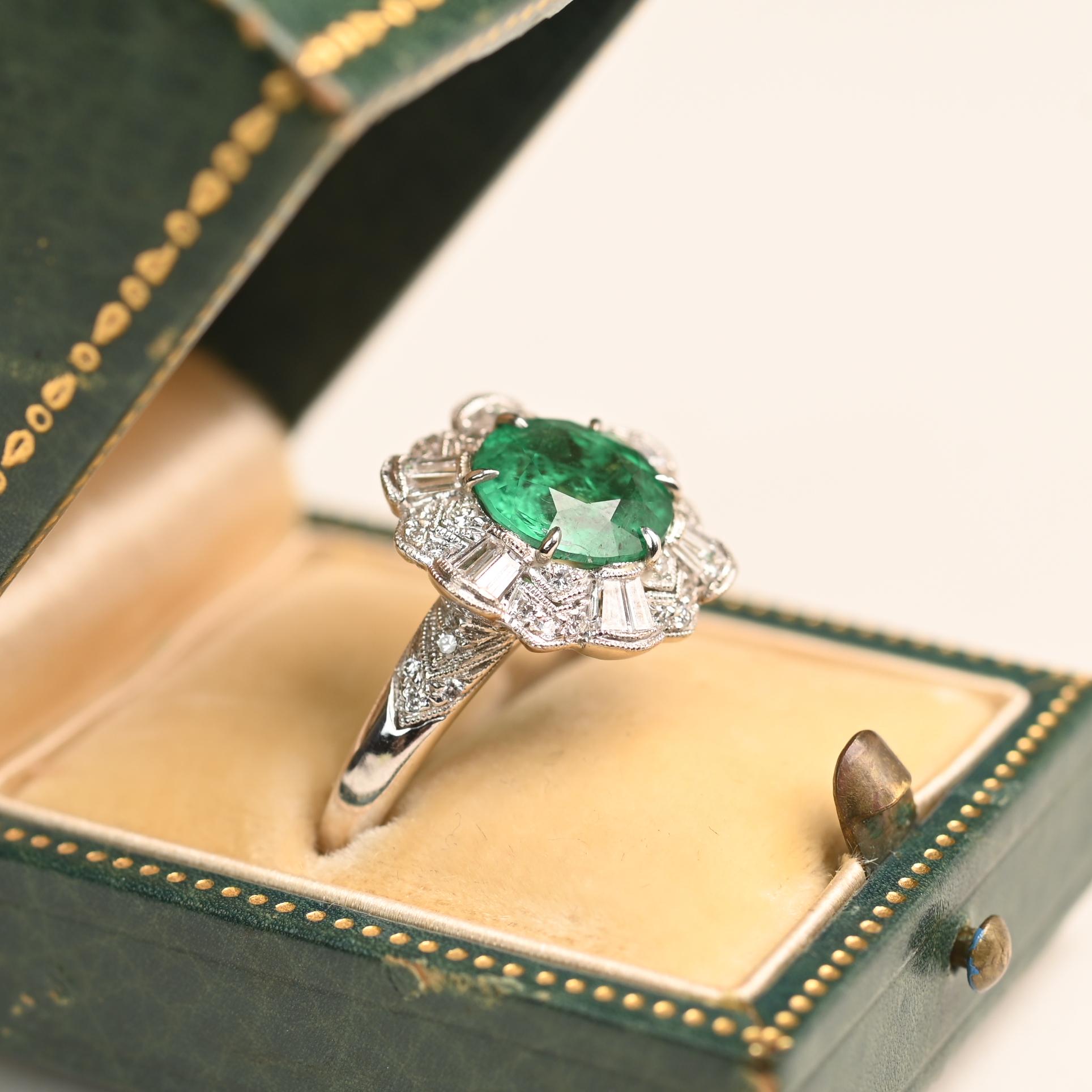 Cette bague exquise est ornée d'une vibrante émeraude verte ronde pesant environ 2,3 carats, solidement sertie dans des griffes. L'émeraude est entourée d'un élégant motif floral orné de diamants de forme mixte et terminé par de délicats détails de
