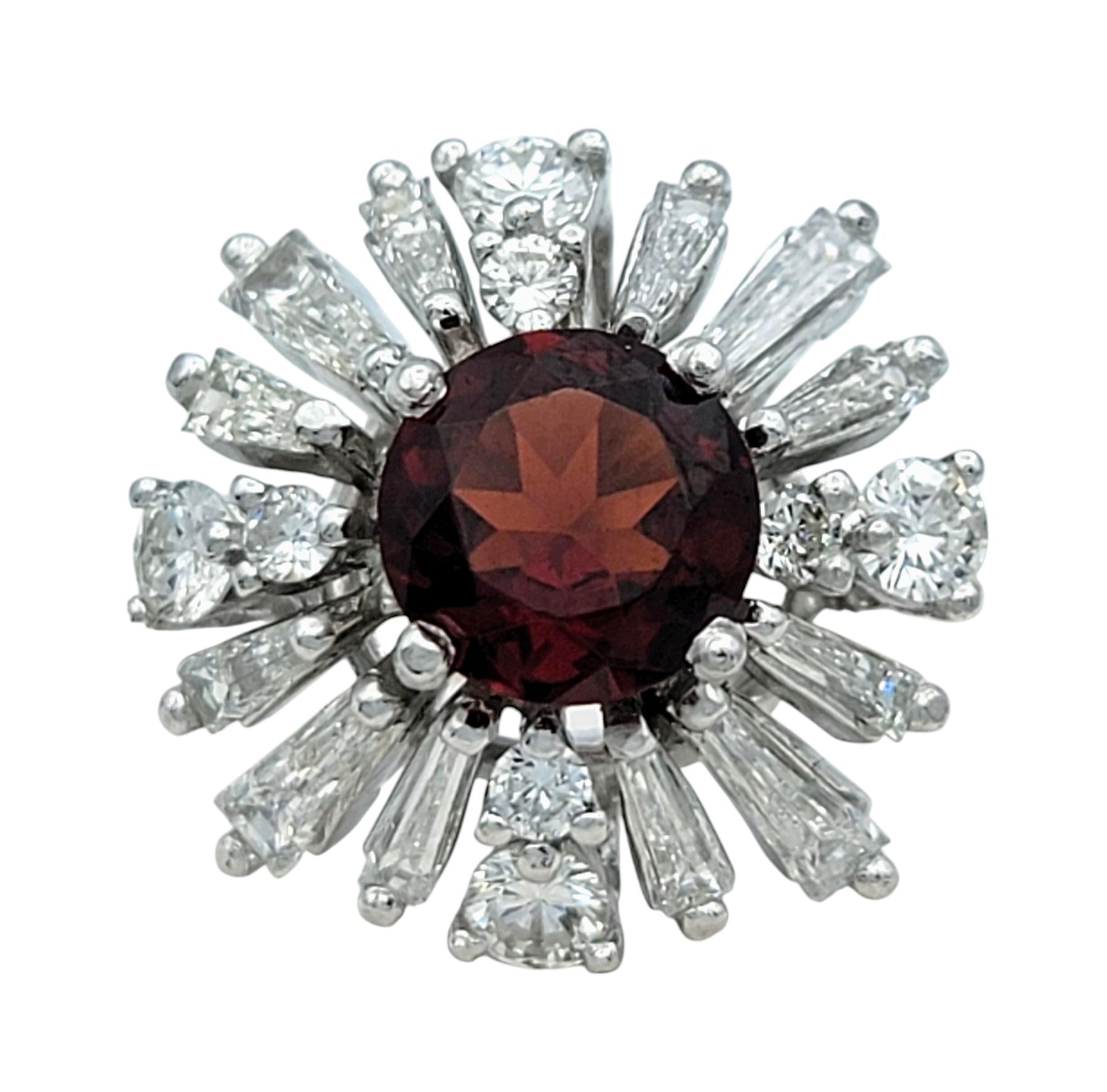 Ring Size: 7

Unleash the allure of vintage-inspired glamour with this stunning garnet and diamond cocktail ring. At its heart lies a vibrant round-cut garnet, radiating a deep, fiery red that captures the eye and evokes timeless sophistication.