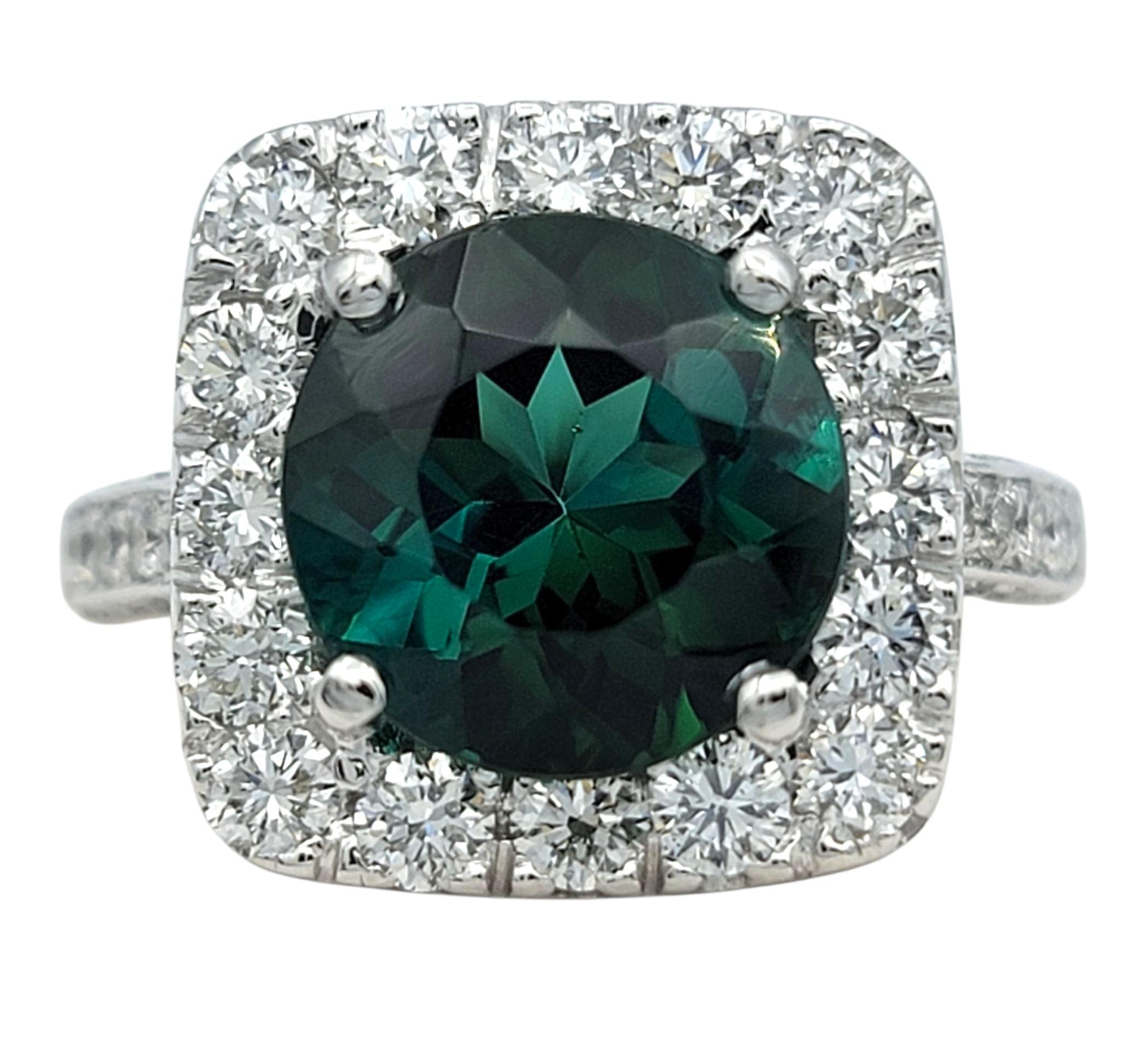 This striking ring features a vivid green tourmaline at its center, radiating rich color and depth from every angle. The gemstone is surrounded by a brilliant squared diamond halo that enhances its glow, creating a captivating contrast between the
