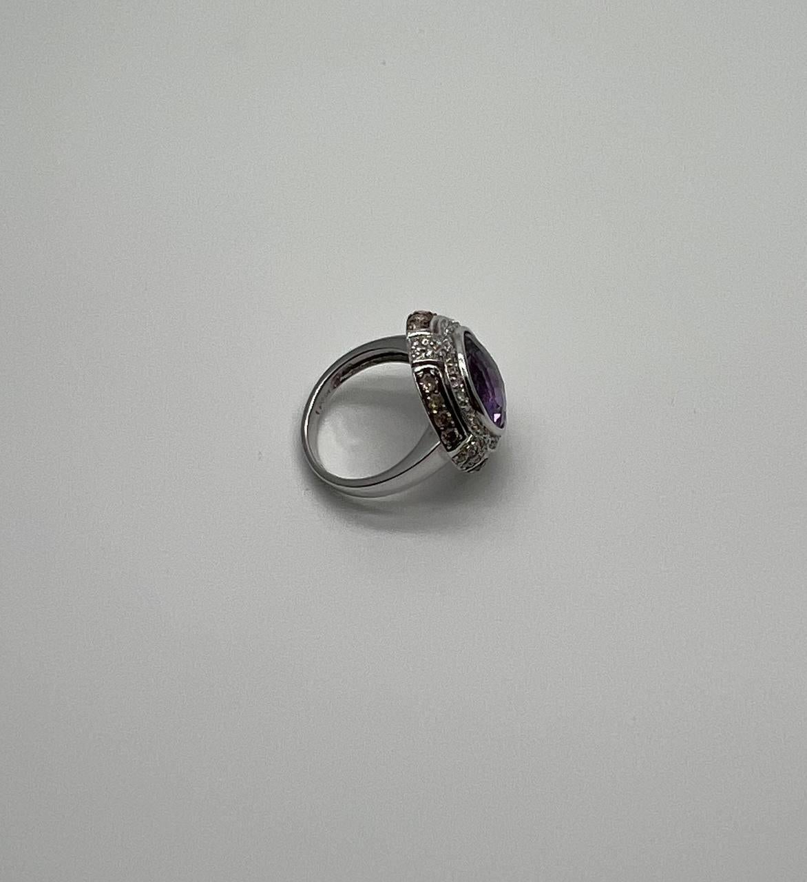 This striking multi-stone ring is crafted in 14k White Gold. It features a round-cut purple amethyst as the centerpiece, surrounded by sparkling white diamonds.
The intricate design showcases the amethyst's vibrant hue, enhanced by the brilliance of