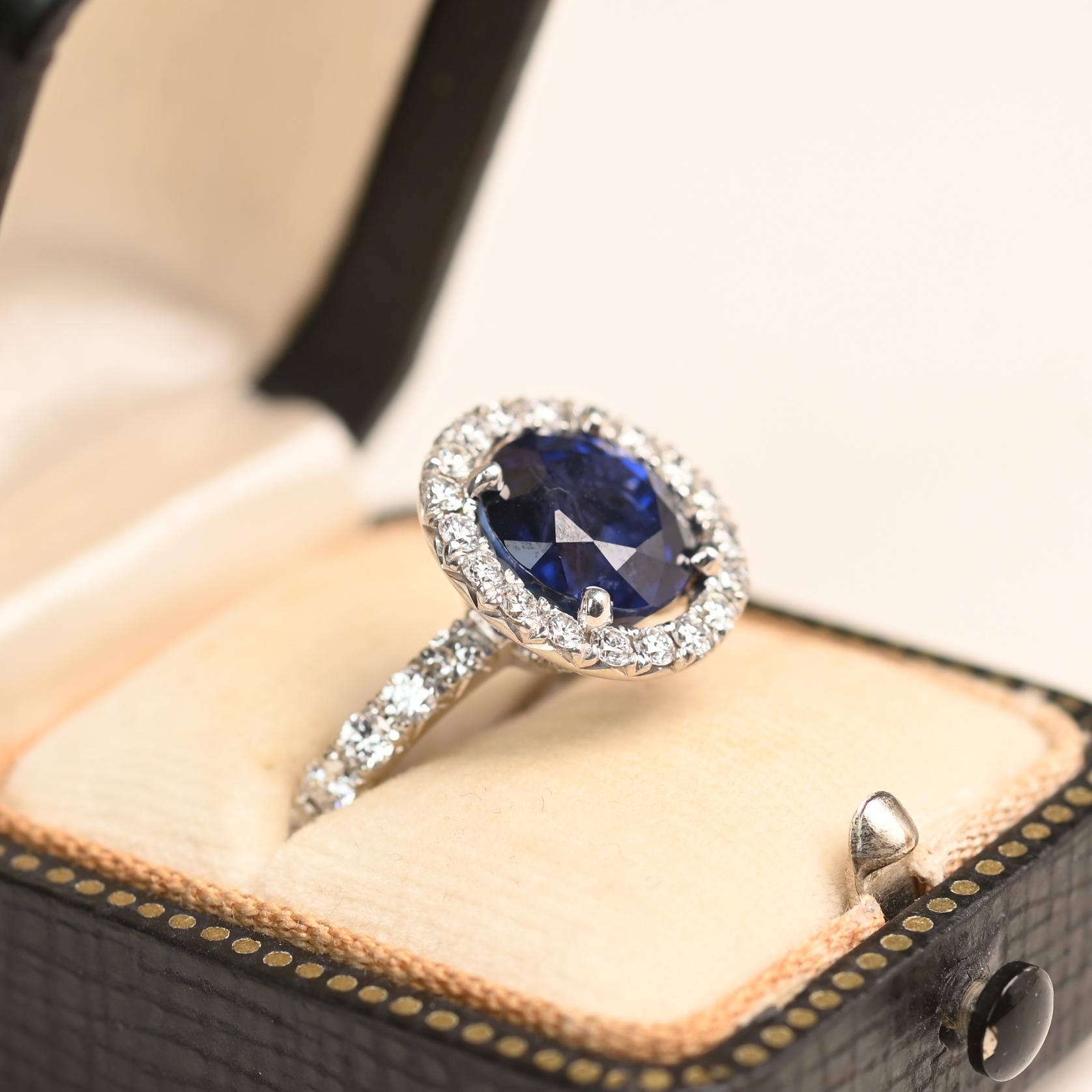 This stunning ring showcases a Ceylon heated sapphire weighing approximately 5.00 carats. The round sapphire is securely set in a prong setting and is encircled by a halo of sparkling round diamonds. Additional diamonds accent the under-gallery and