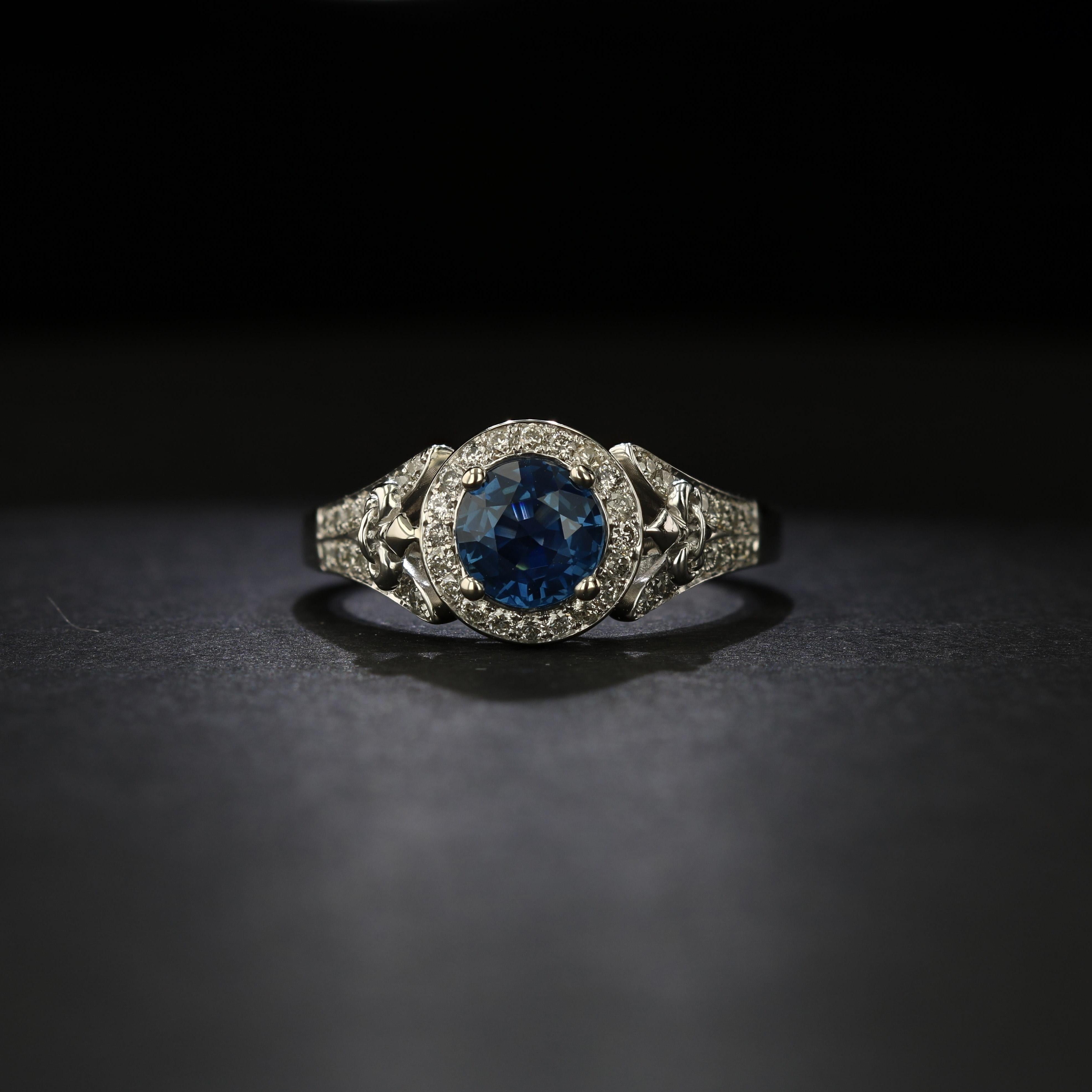 This 14k white gold sapphire and diamond ring is a wonderful choice for an alternative engagement ring. In the center is a round sapphire weighing approximately 1.22 carat. The sapphire has a rich blue hue and excellent clarity. Surrounding the