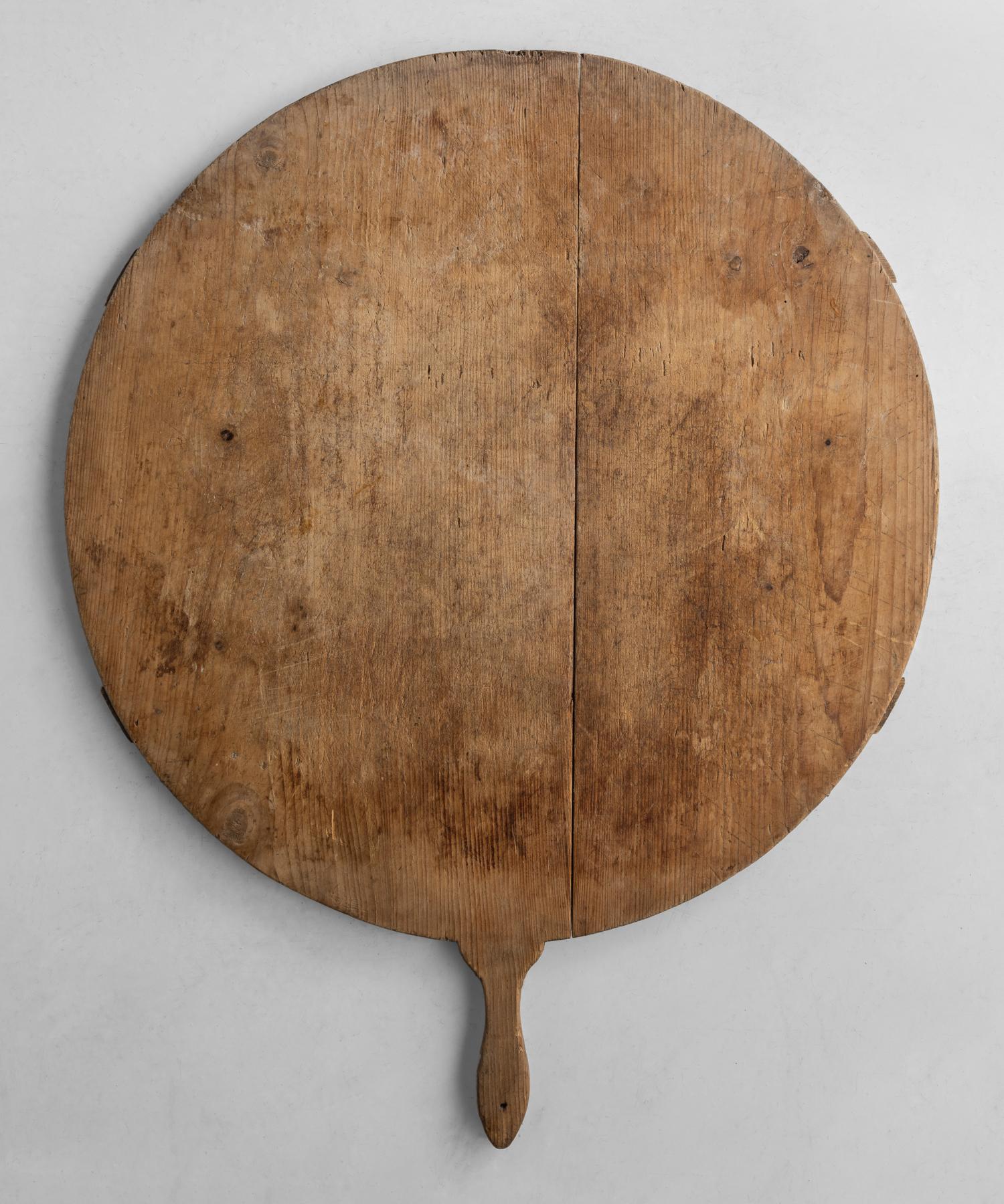 Round cutting board, America, circa 1900.

Single-sided, beautifully worn Primitive form with stretcher support underneath.

Measures: 25.25