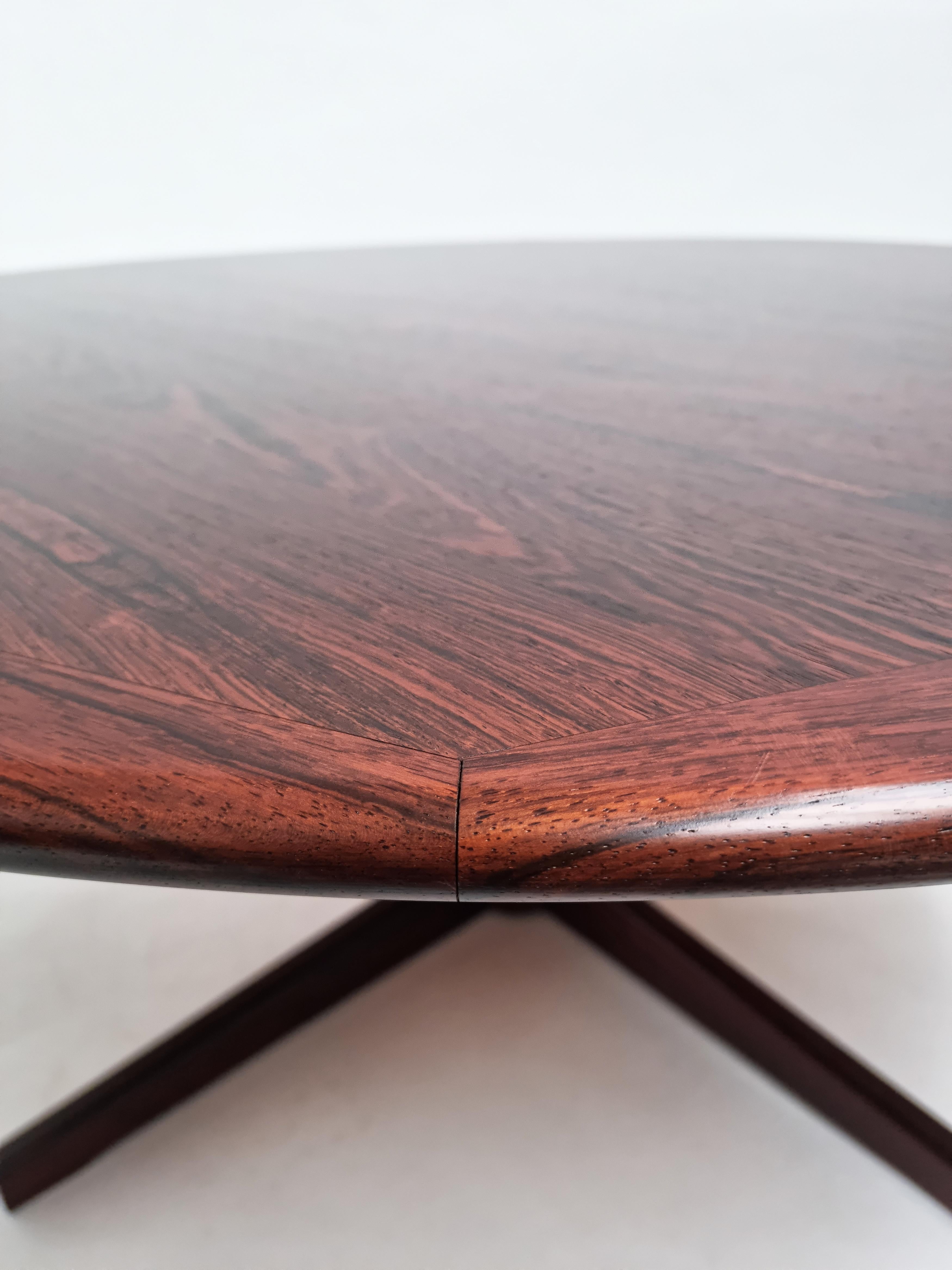 Circa 1960s round Danish coffee table with a compound beveled edge along the outer circumference. Beautiful graining to the book matched veneer, rich reds and blacks.