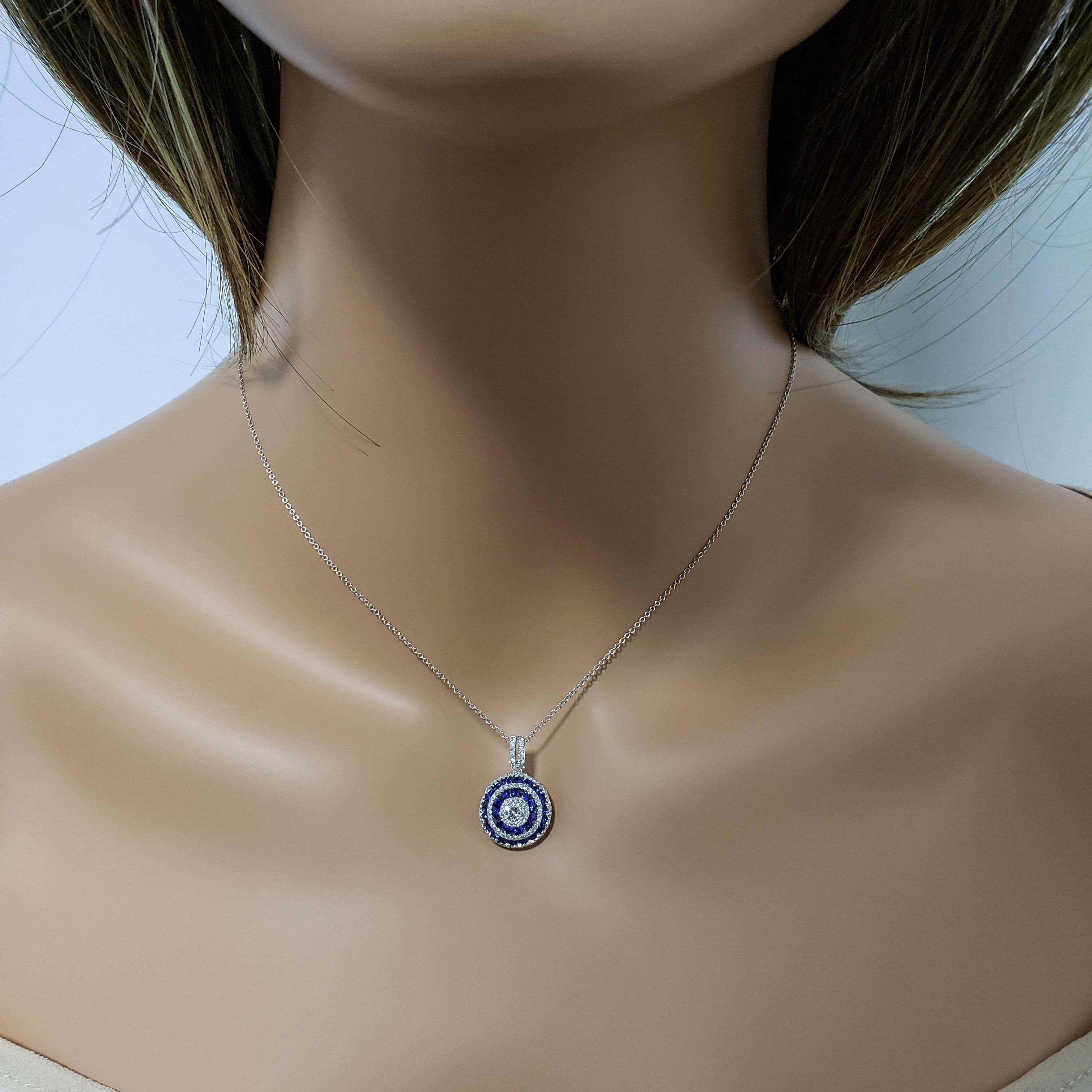A unique and stylish pendant necklace showcasing a round brilliant diamond center, accented by rows of round diamonds and blue sapphires. Diamonds weigh 0.63 carats total; blue sapphires weigh 1.17 carats total. Made in 18k white gold.

Roman